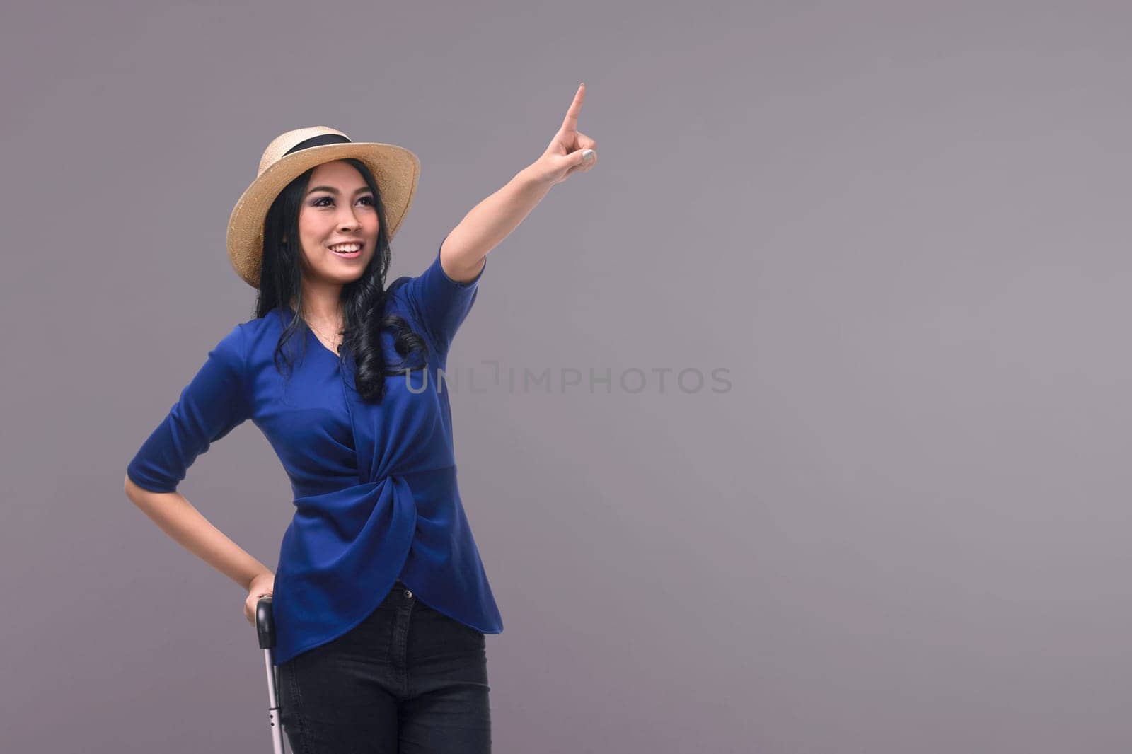 Portrait of asian woman tourist carrying suitcase against bright background