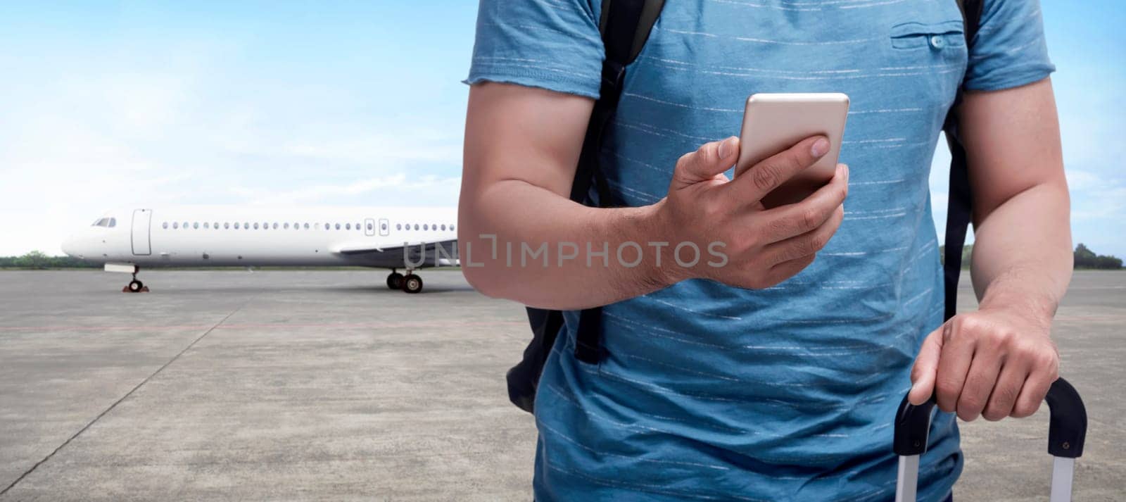 Backpacker asian man carrying bag with phone on his hand on runway airplane