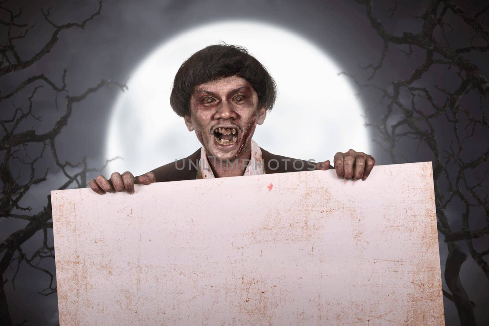 Scary asian zombie man with wounded face with empty banner at dark night