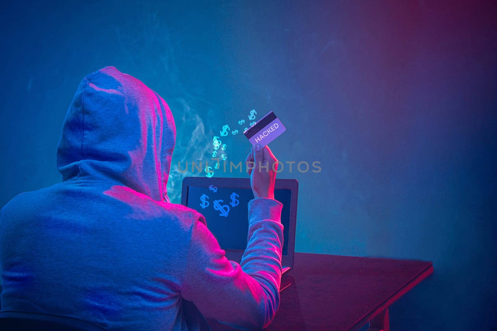 Hooded computer hacker stealing information with laptop. Concept of threat