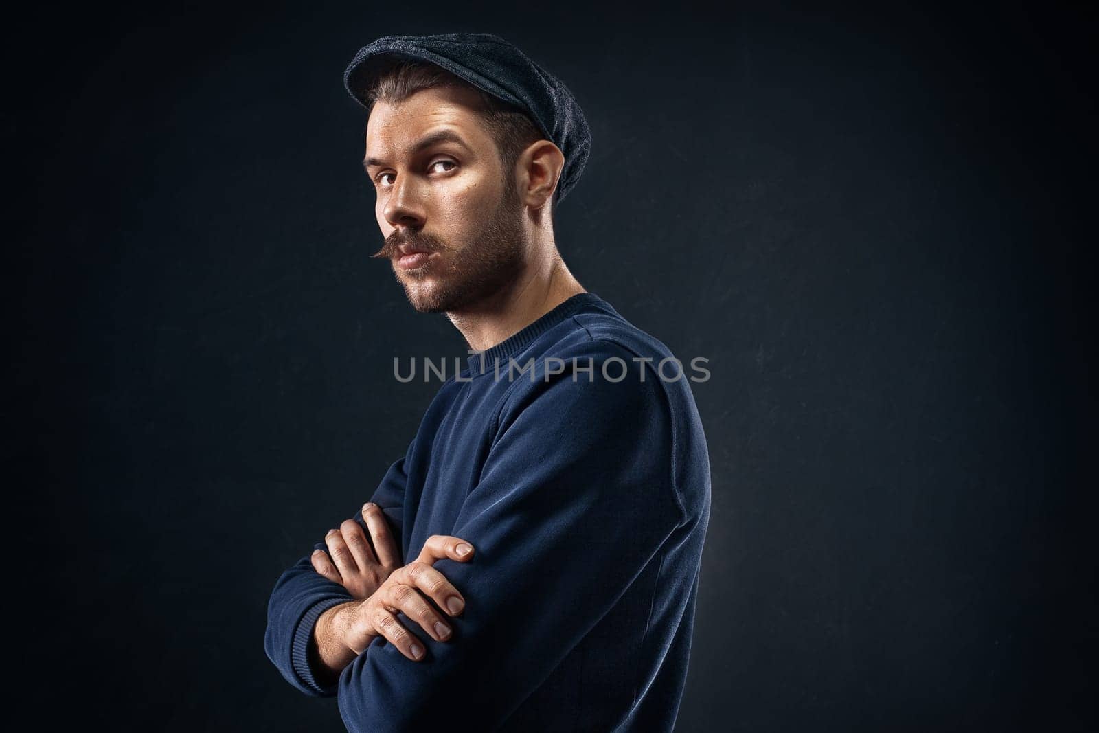 The young man in cap looking away on black background