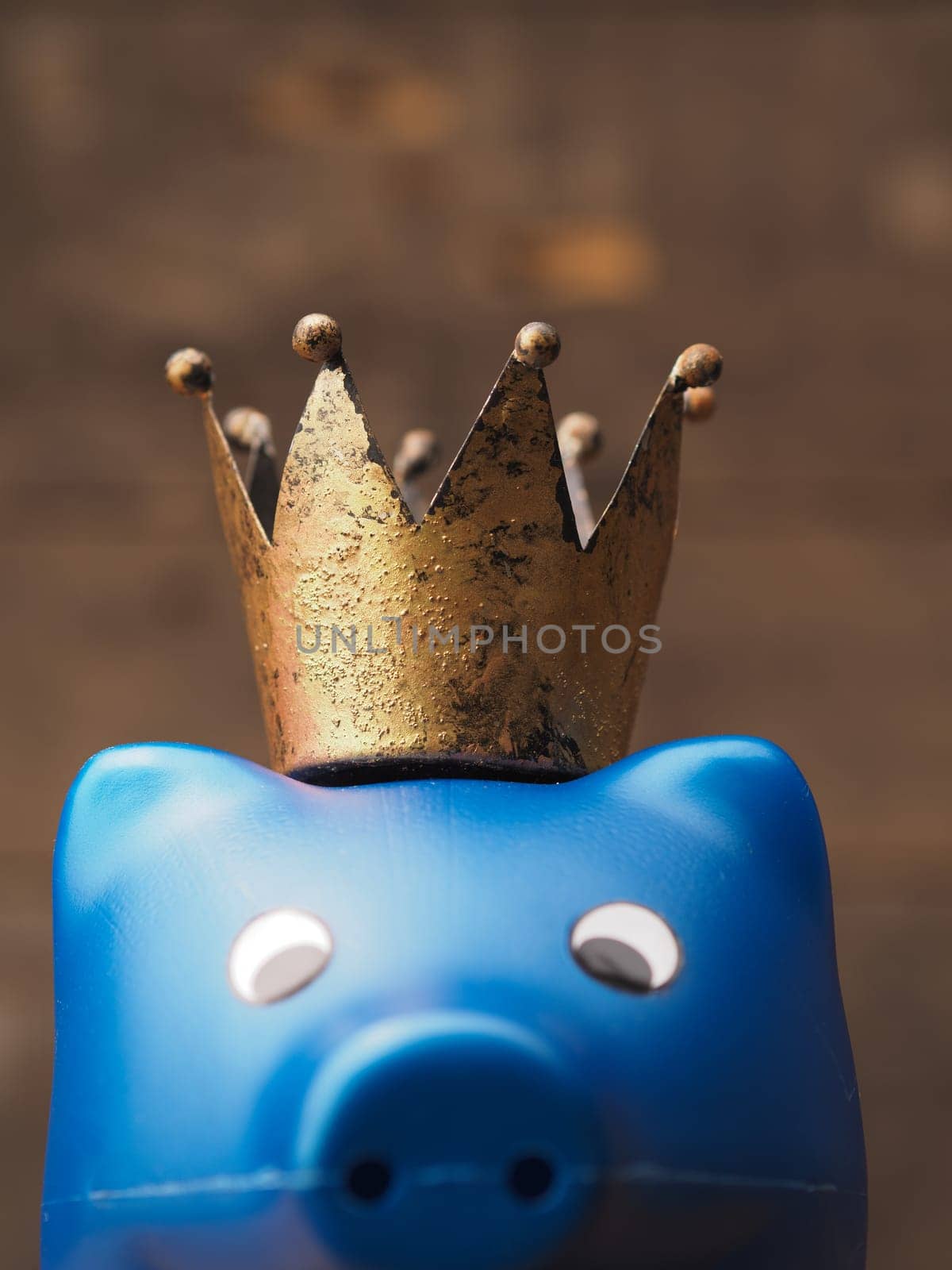 Blue piggy bank with an old crown, saving money concept with selective focus on the crown