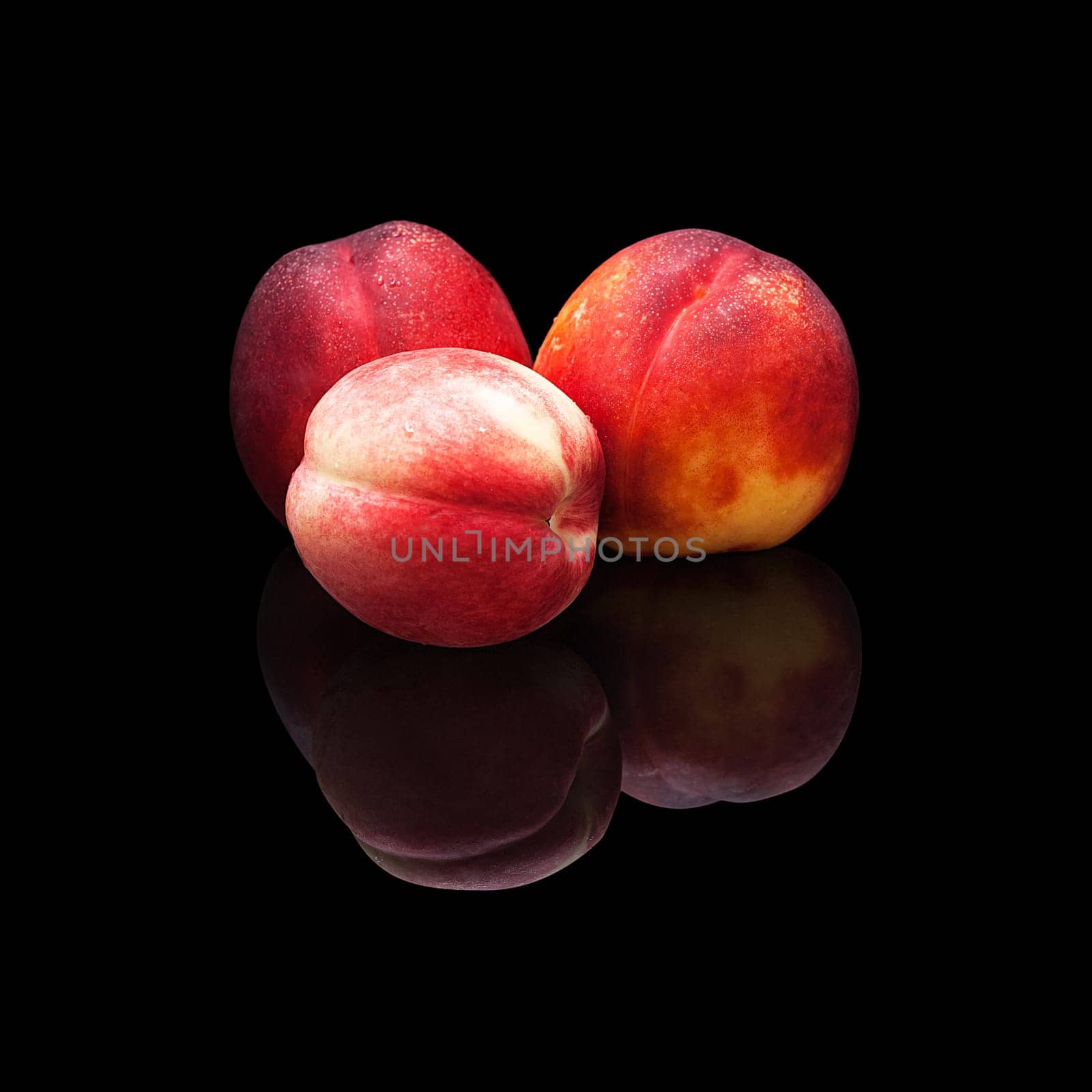 Three ripe nectarines on a black background isolated with real reflection