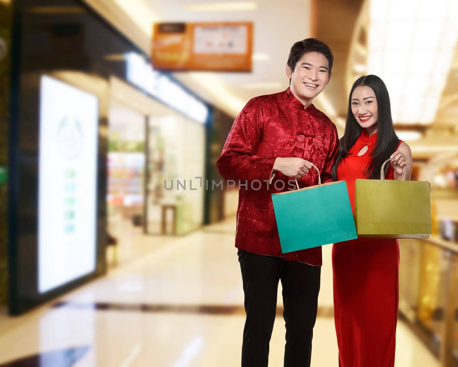 Asian couple holding shopping bag with mall background