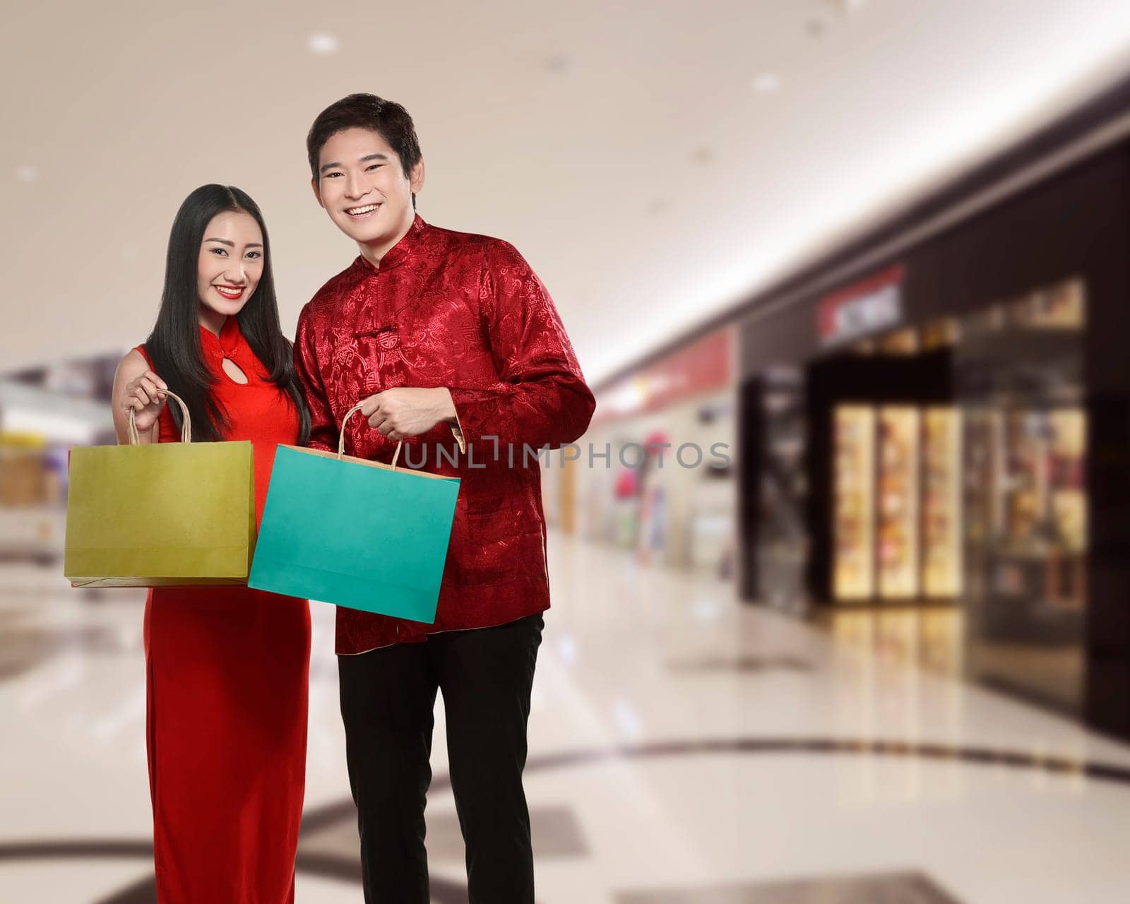 Asian couple holding shopping bag with mall background