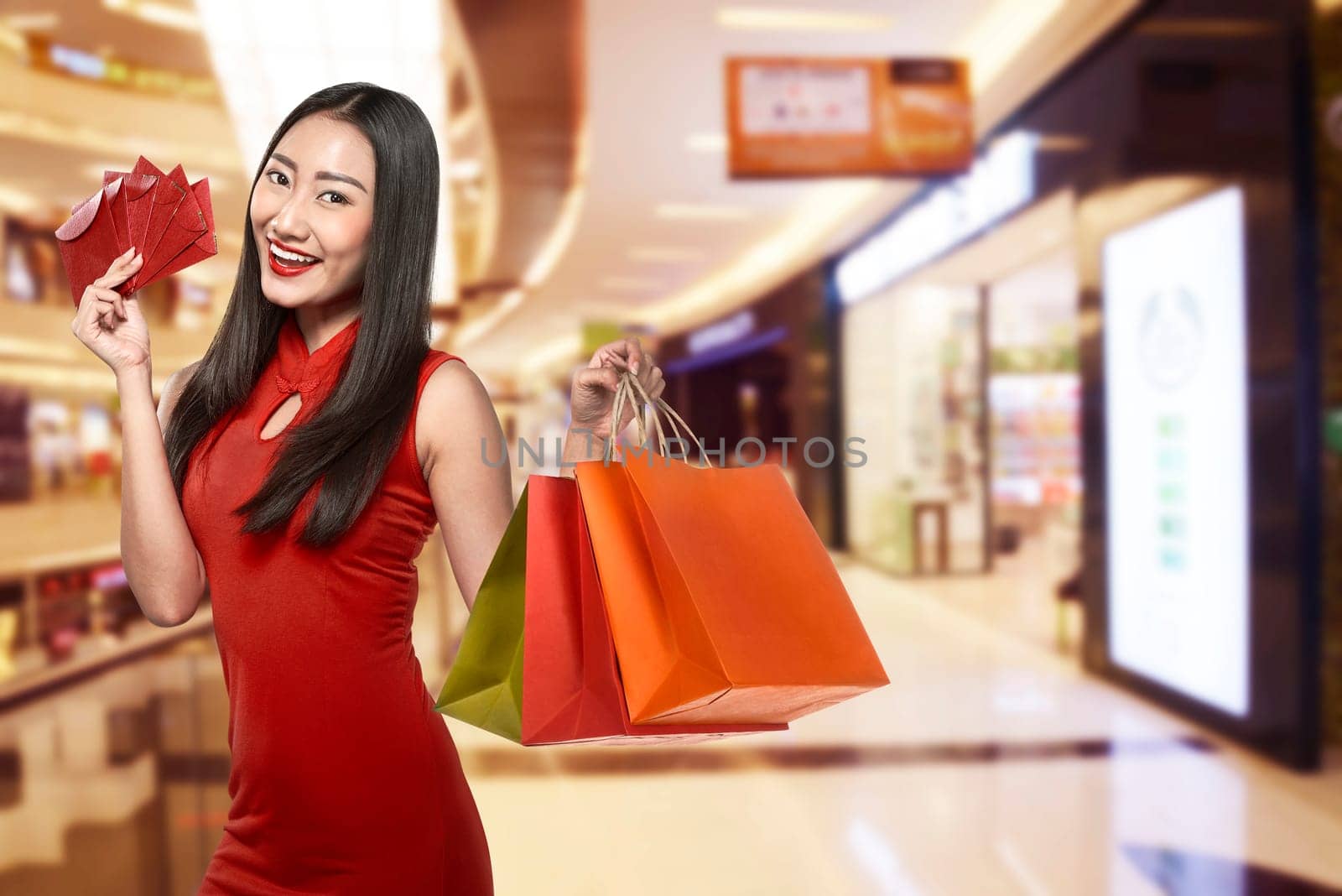 Chinese woman wearing traditional clothes holding shopping bag with mall background