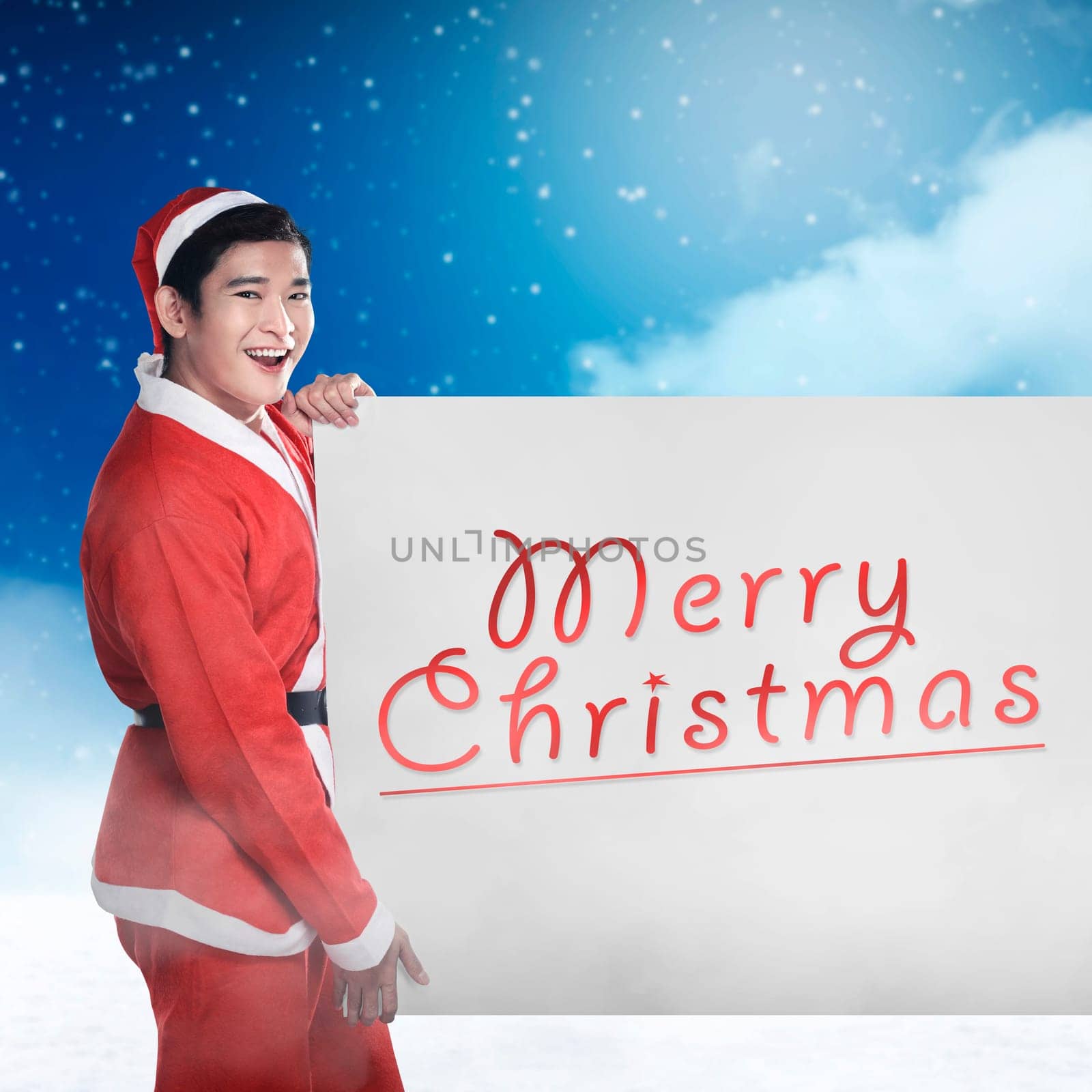 Asian man wearing santa claus costume holding banner with merry christmas writing