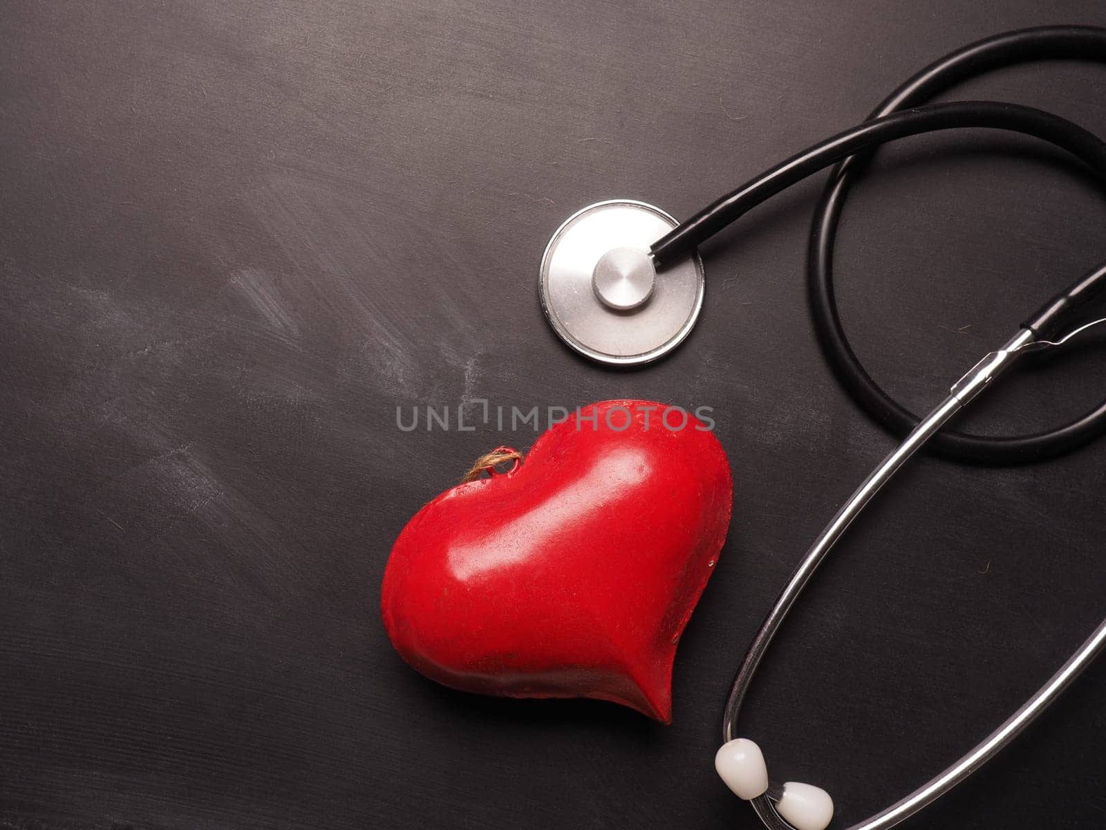 Red heart shape with a stethoscope on a chalkboard with space for text