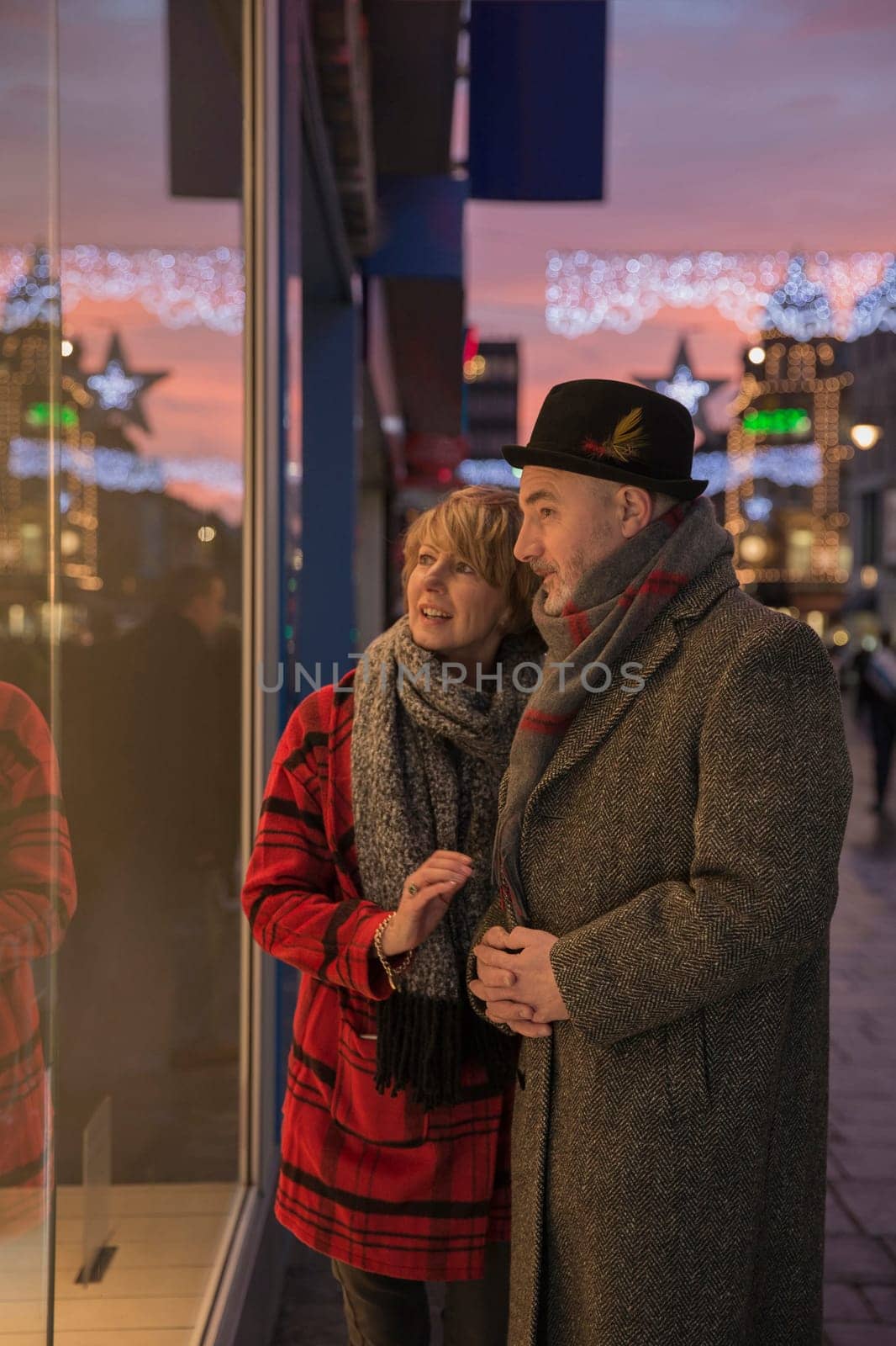Mature couple are enjoying some winter shopping on an evening at christmas time.