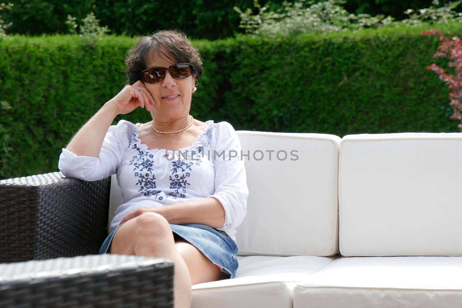 portrait of  smiling middle age woman with sunglasses  sitting in garden at home