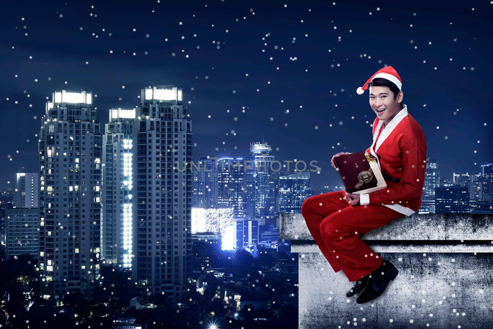 Asian man wearing santa claus costume sit on the rooftop. Christmas present