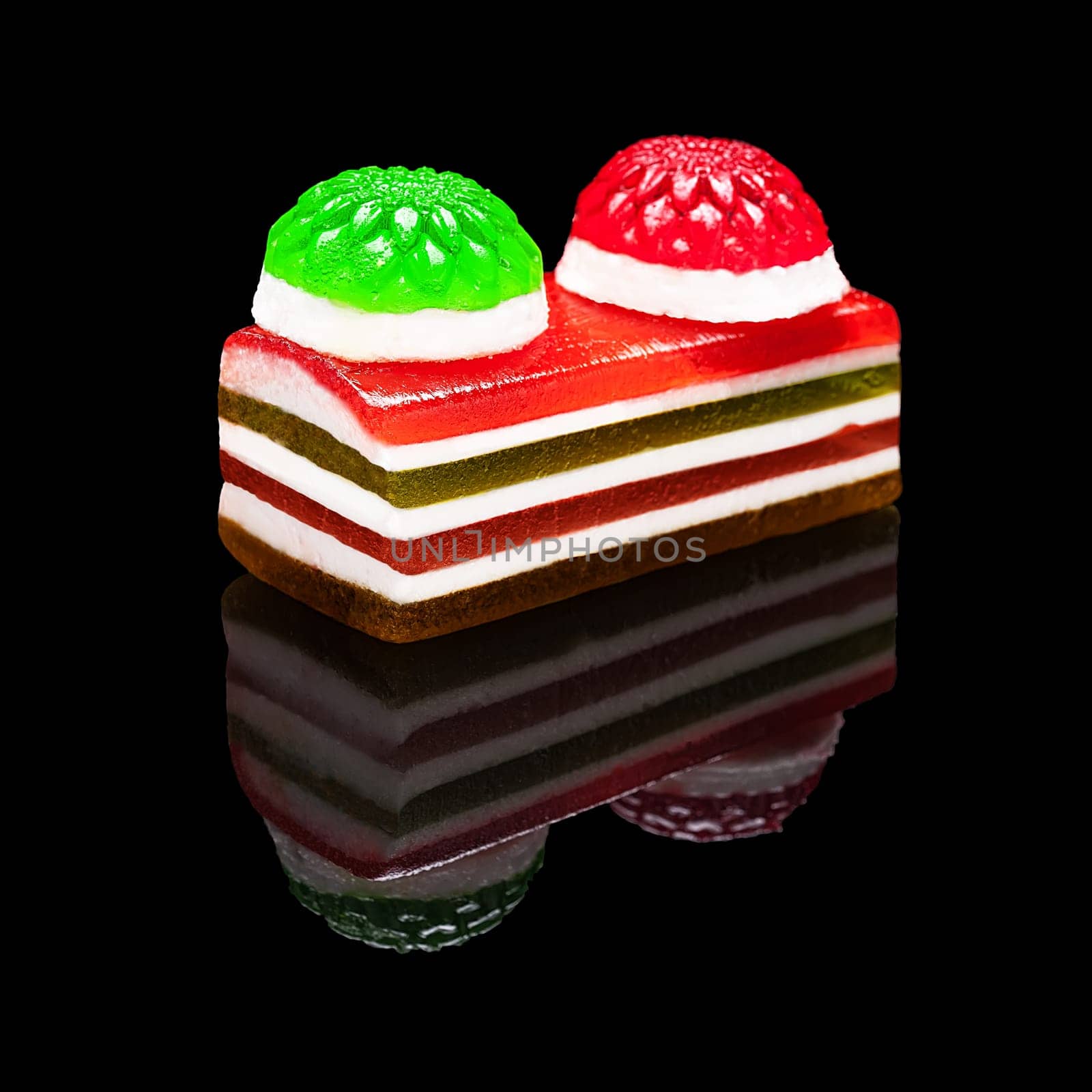 Rectangular piece of colored marmalade isolated on black glossy background with real reflection