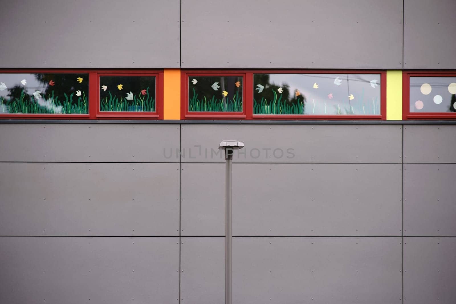 The narrow windows of a modern building with glued flower decorations and a lantern in front of the façade.