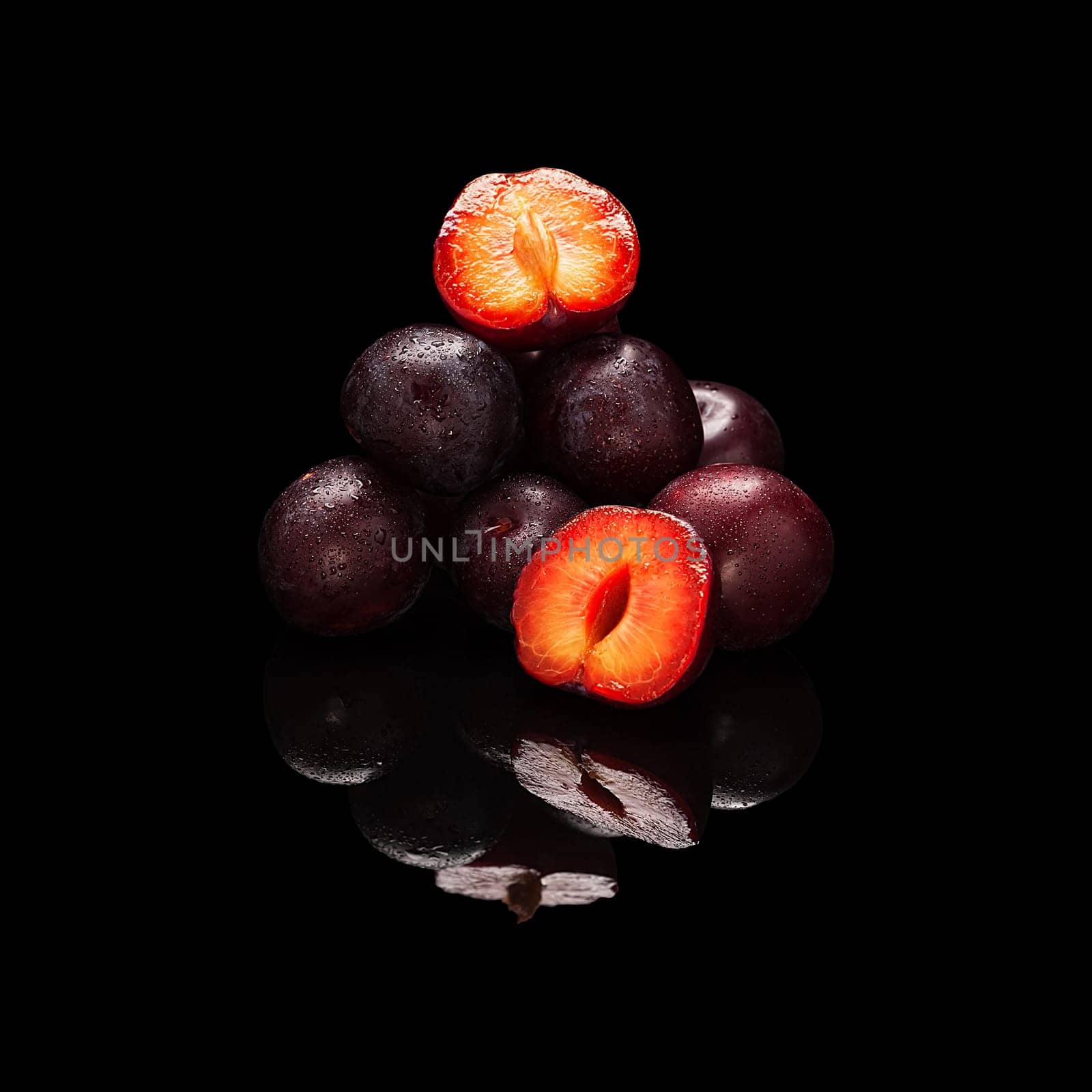 Stack of purple plums isolated on a black glossy background with real reflection