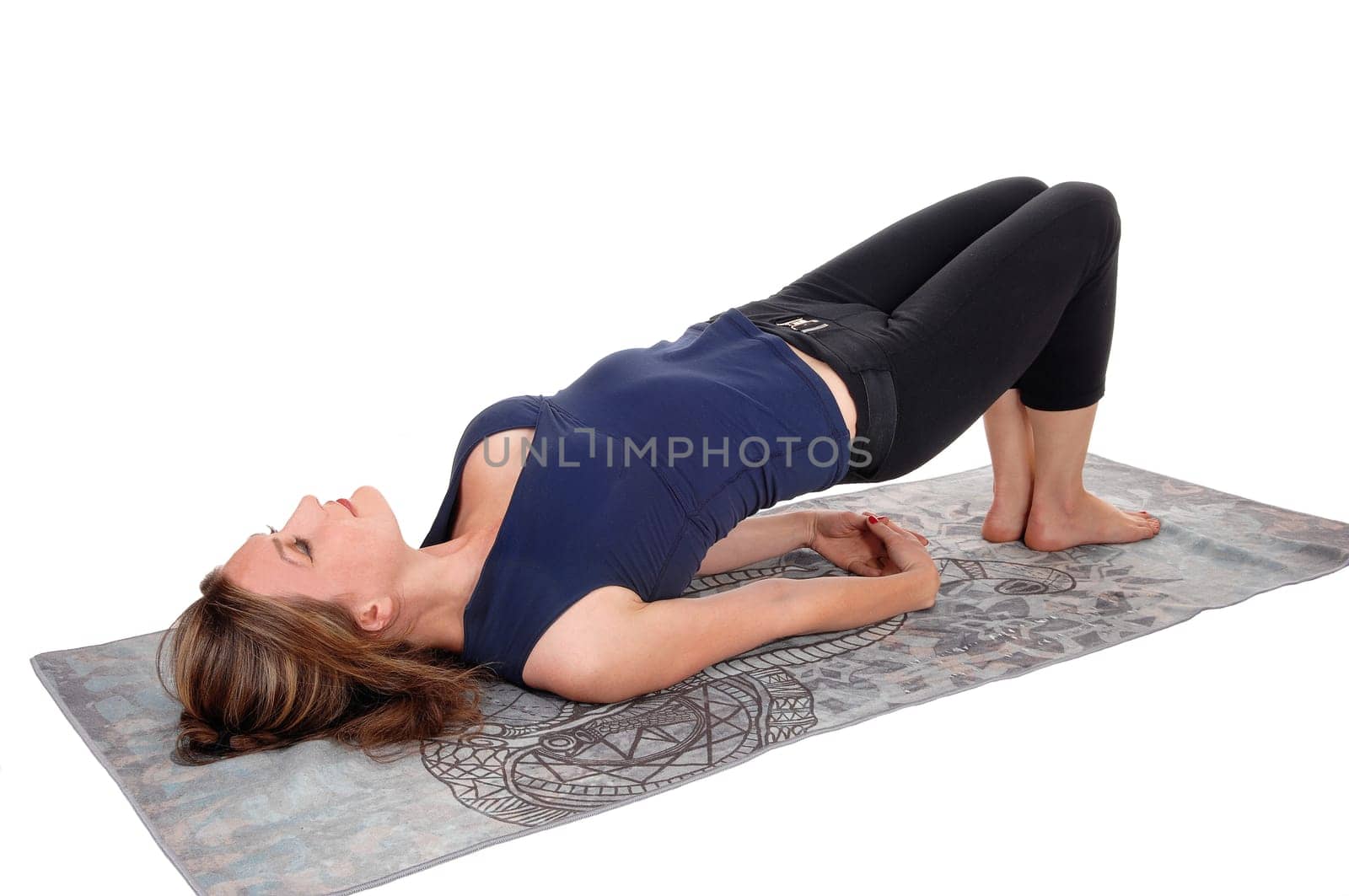 A slim young woman stretching her body after some exercising, lying.on her back, with bum lifted up, isolated for white background.