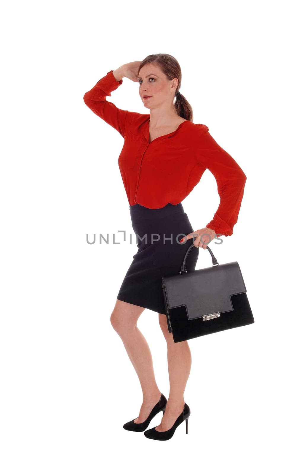 A gorgeous young business woman walking in a red blouse and black .skirt, holding her black purse, isolated for white background.