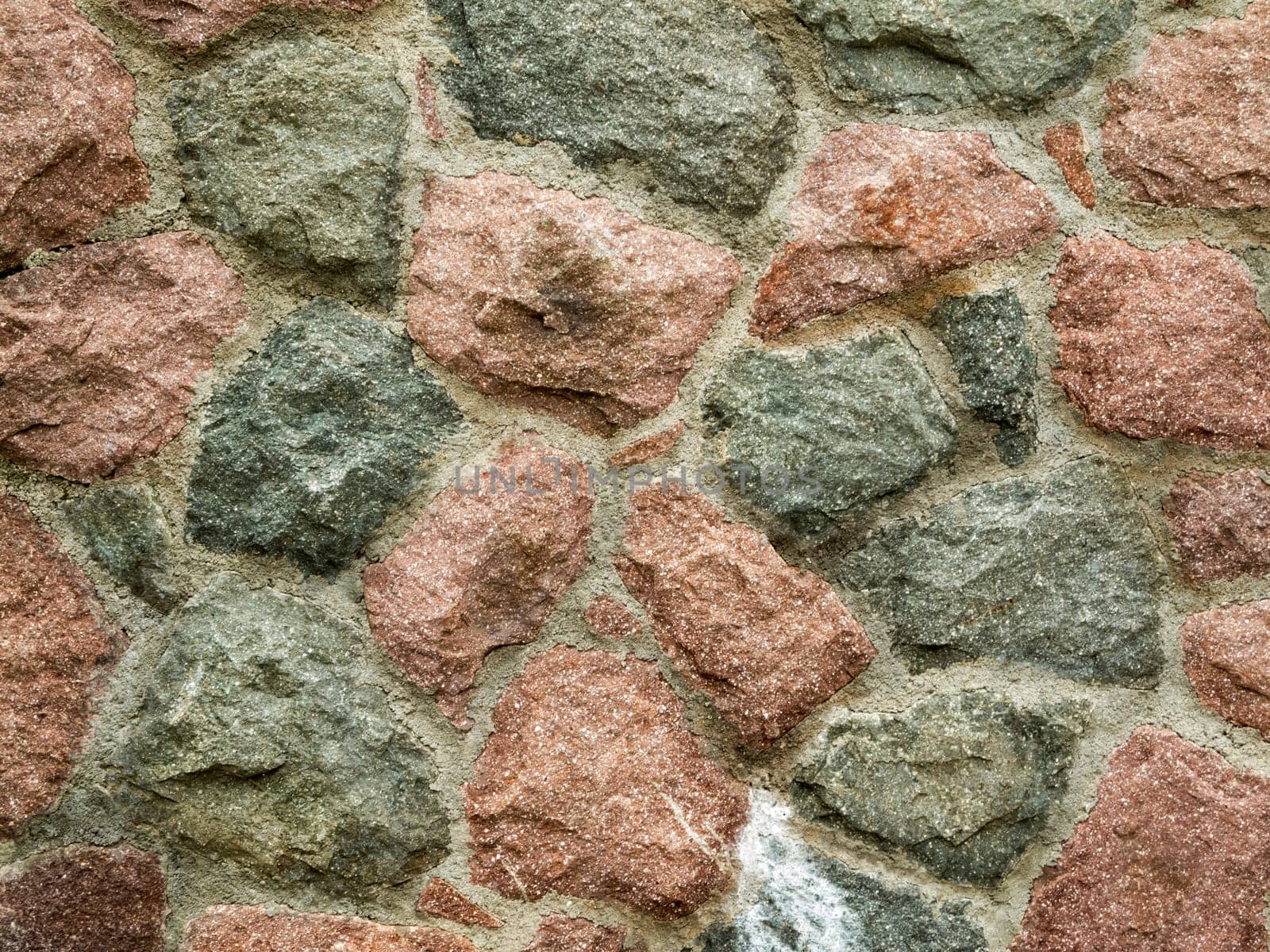 Format-filling view of a brick field-stone wall with cement joints.