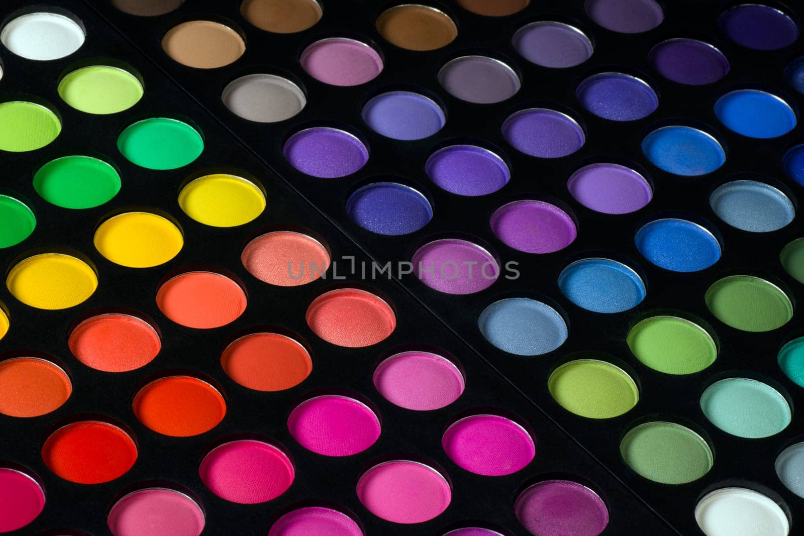 Colorful eye shadow palette is on black background.