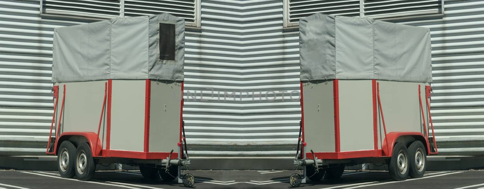 Old horse transport trailer in front of a metal wall..
