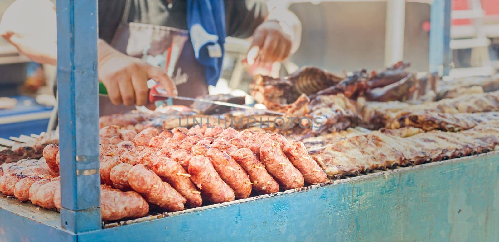 Sausages on the grill. Blurred in the background the Cook and other meats to cook.