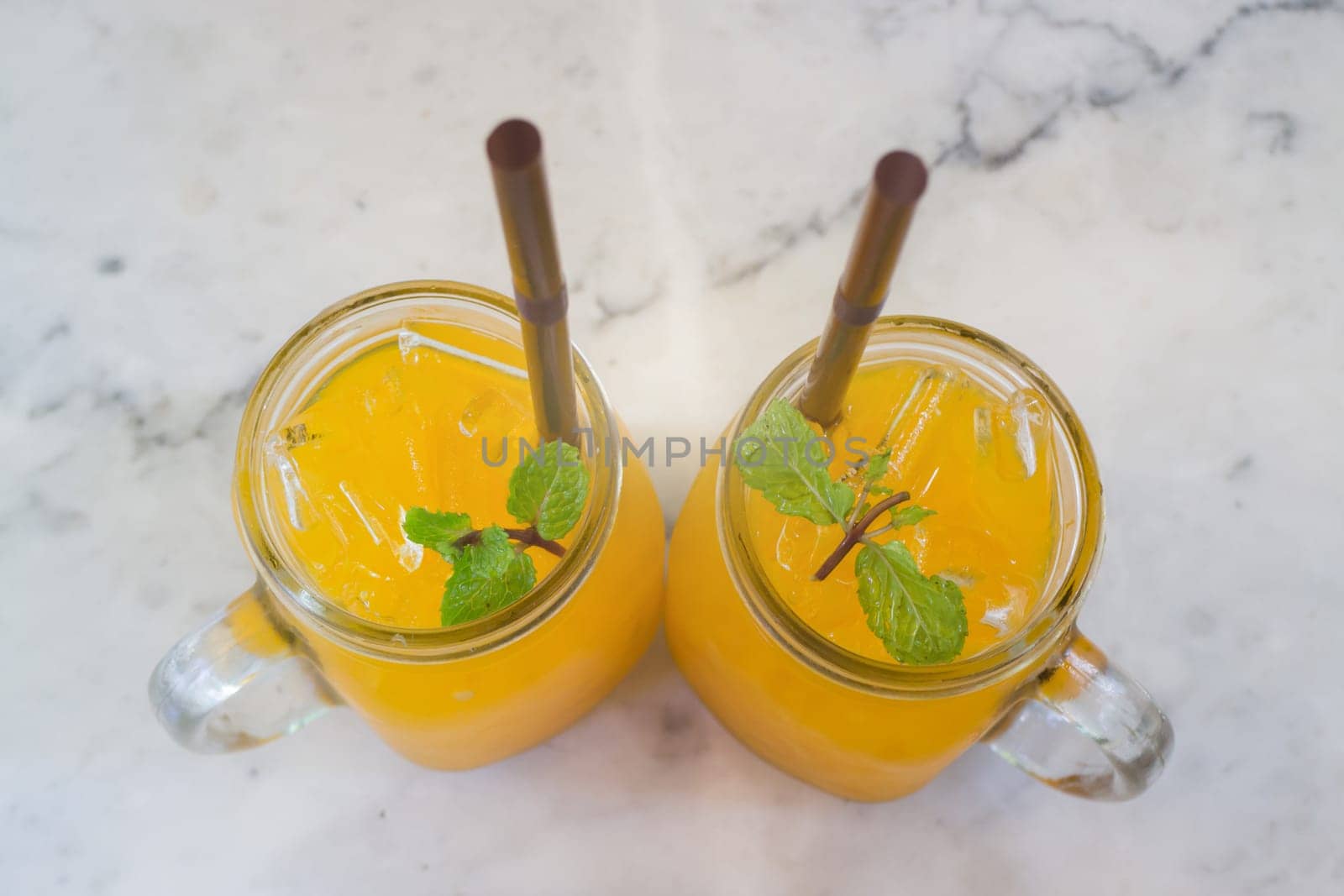 Orange juice with ice cube on marble table, stock photo