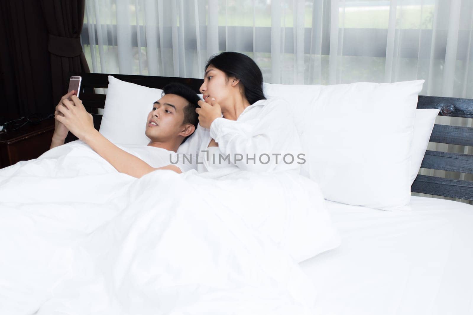 Couple using smartphone on the bed in the morning, smile