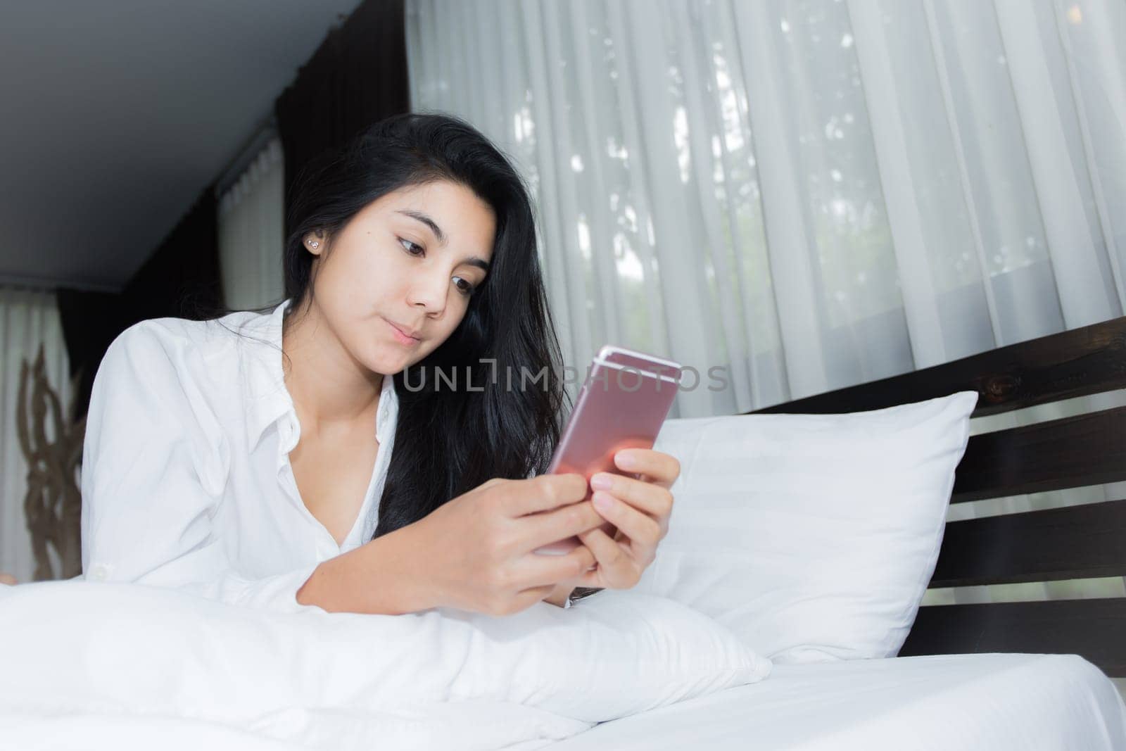 Young Asian woman playing puppy doll on the bed in morning bedroom, alone and lonely