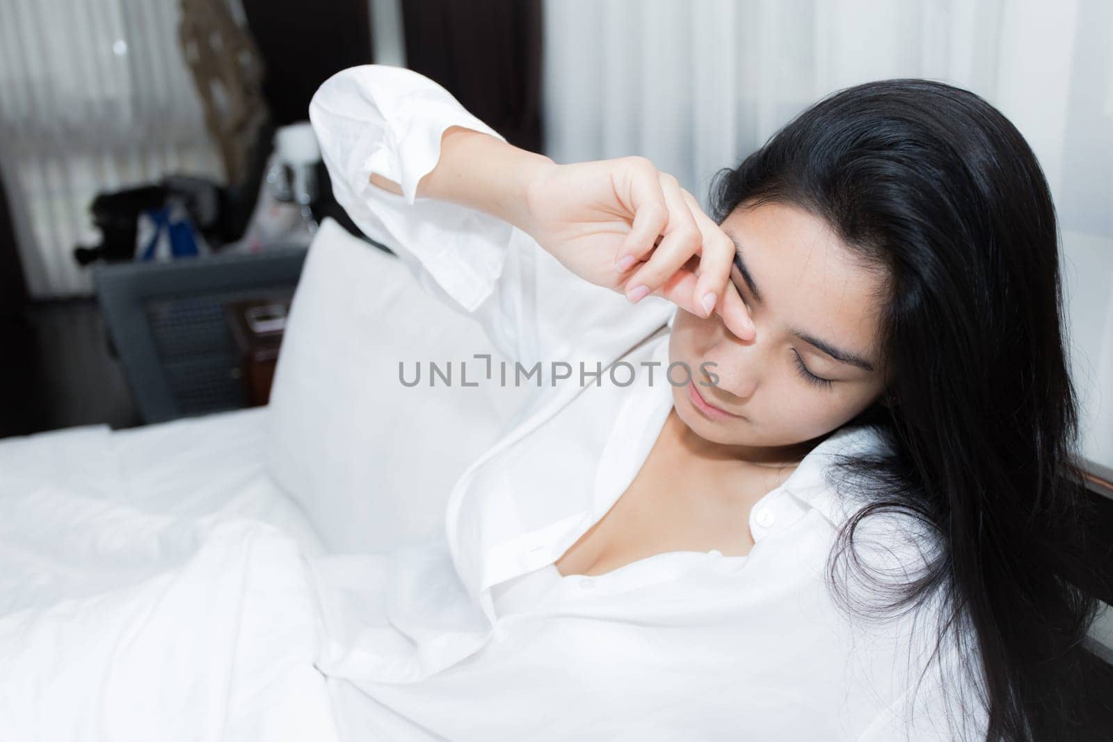 Young Asian woman playing puppy doll on the bed in morning bedroom, alone and lonely