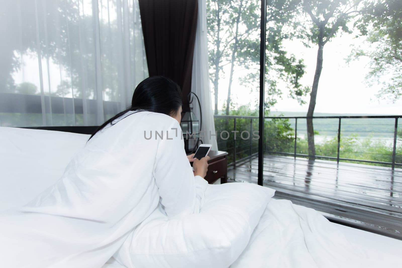 Young Asian woman playing puppy doll on the bed in morning bedroom, alone and lonely