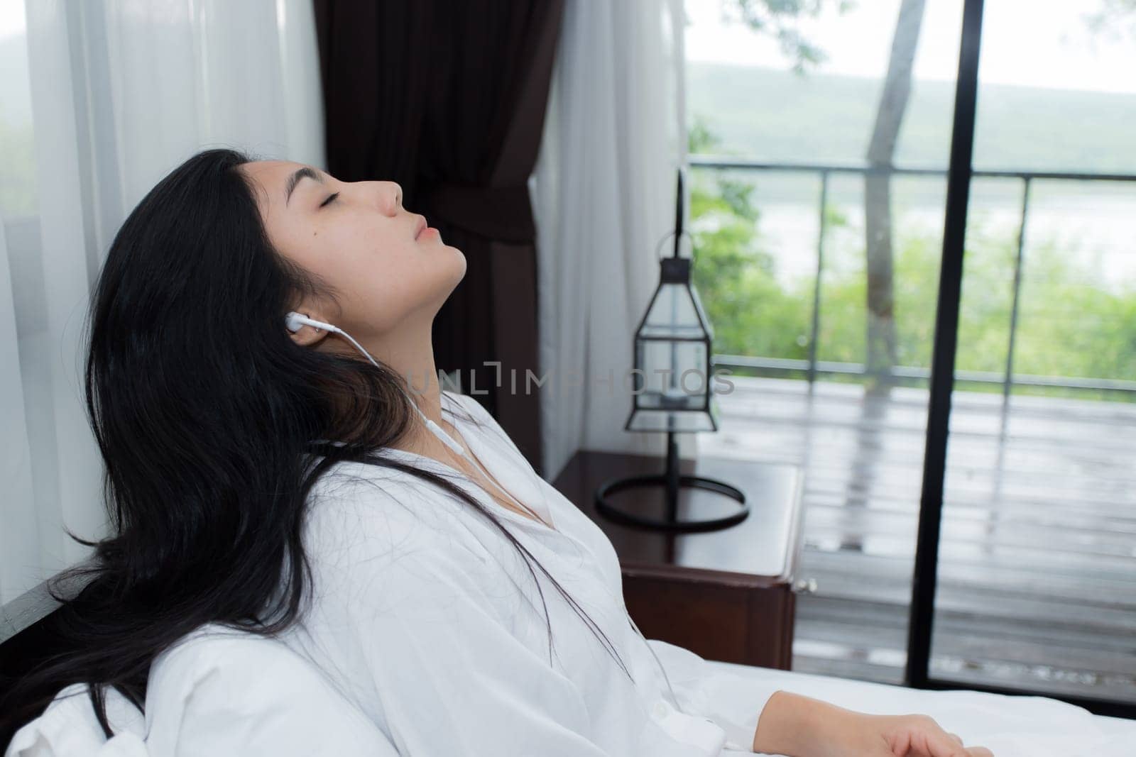 Young Asian woman playing puppy doll on the bed in morning bedroom, alone and lonely
