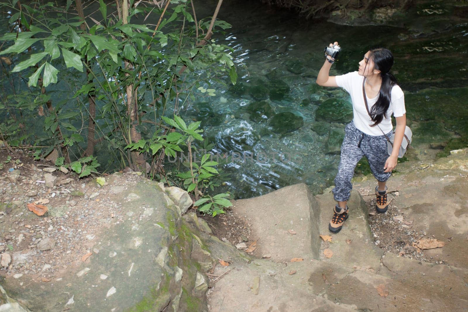 Young asian woman taking photos in autumn forest with camera