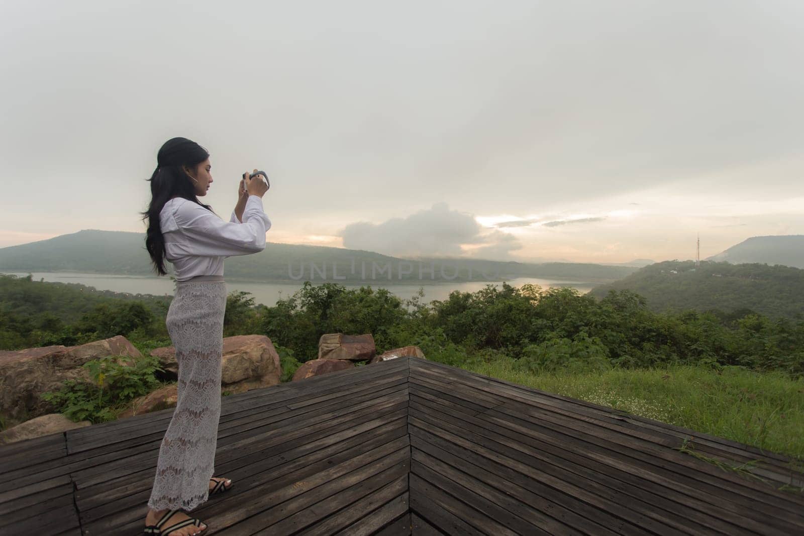 Young asian woman hiker stops to tie her shoe on a summer hiking trail in forest.