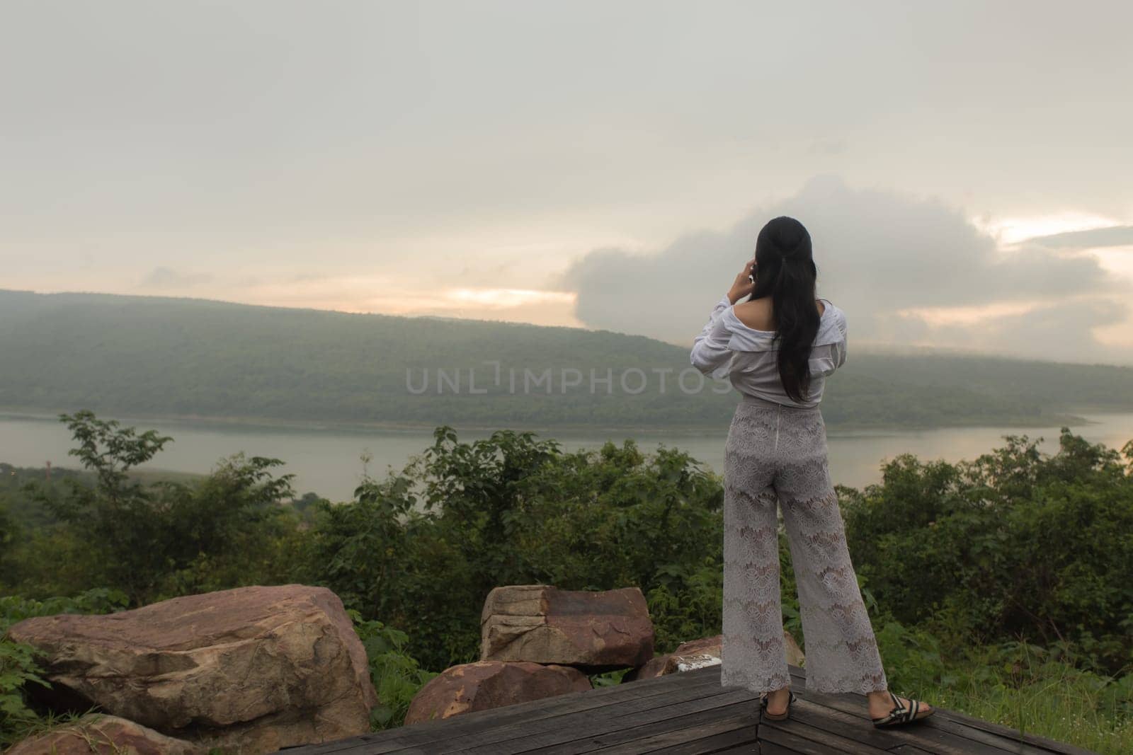 Young asian woman hiker stops to tie her shoe on a summer hiking trail in forest.