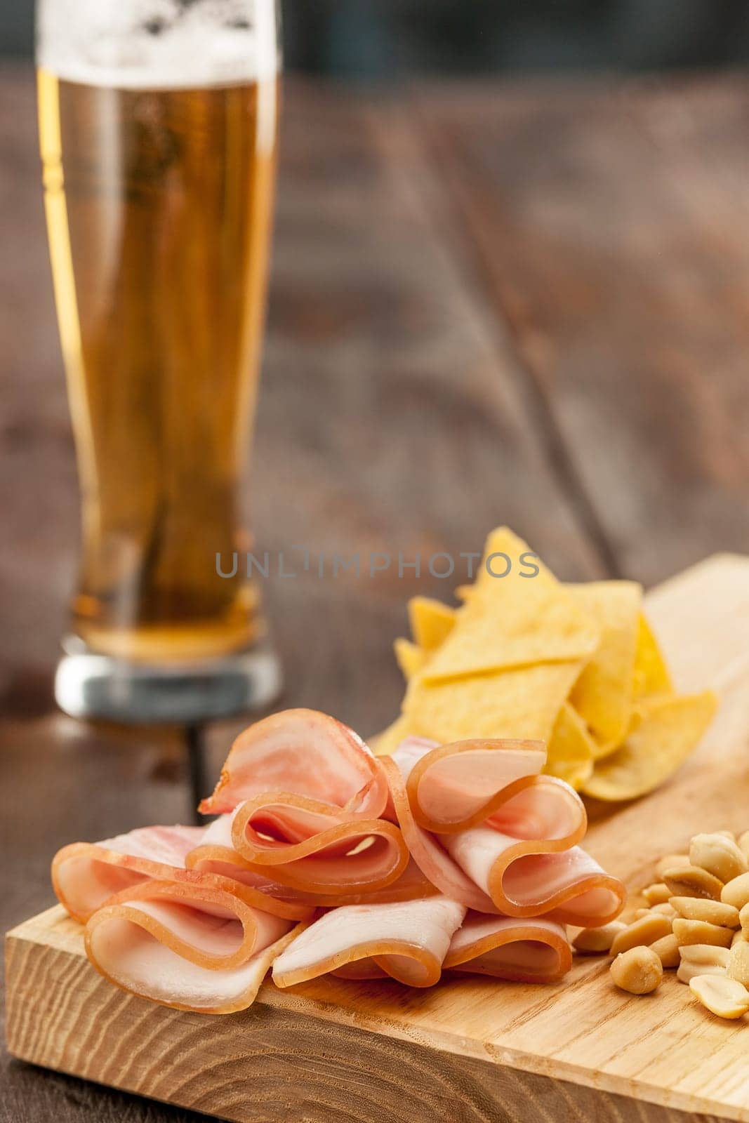 The glass of Beer and potato chips, pistachios isolated on a white