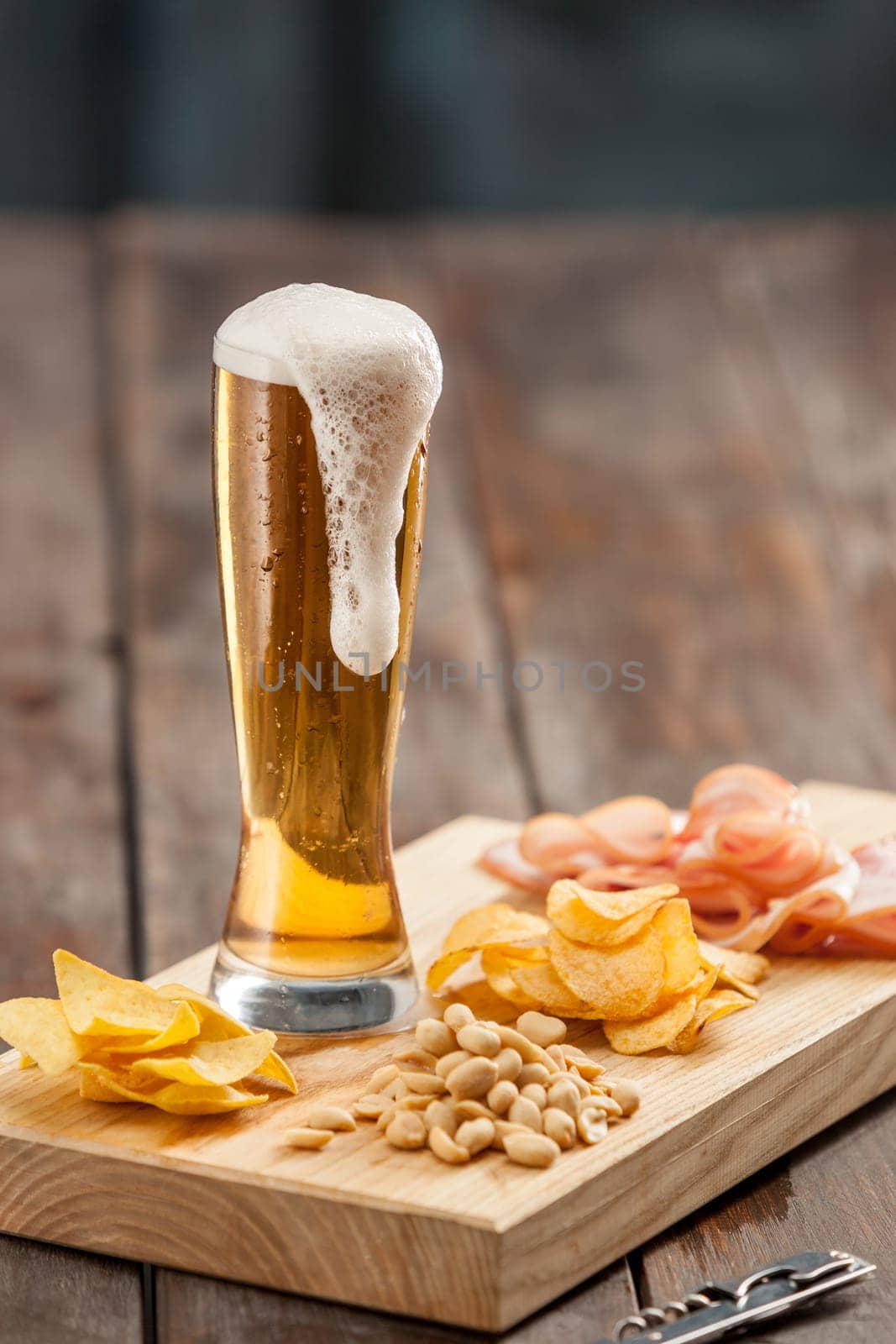 The glass of Beer and potato chips, pistachios isolated on a white