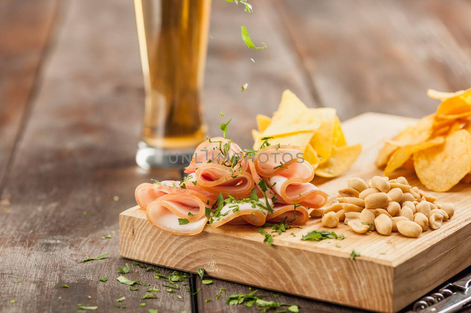 The glass of Beer and potato chips, pistachios isolated on a white