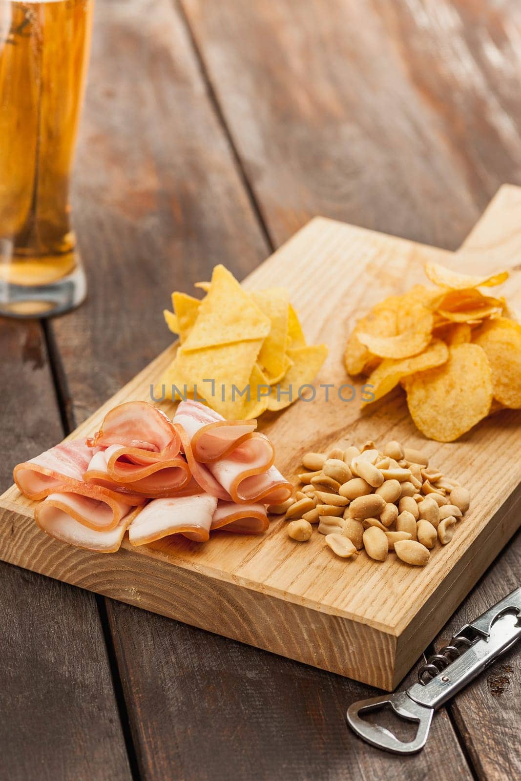 The glass of Beer and potato chips, pistachios isolated on a white