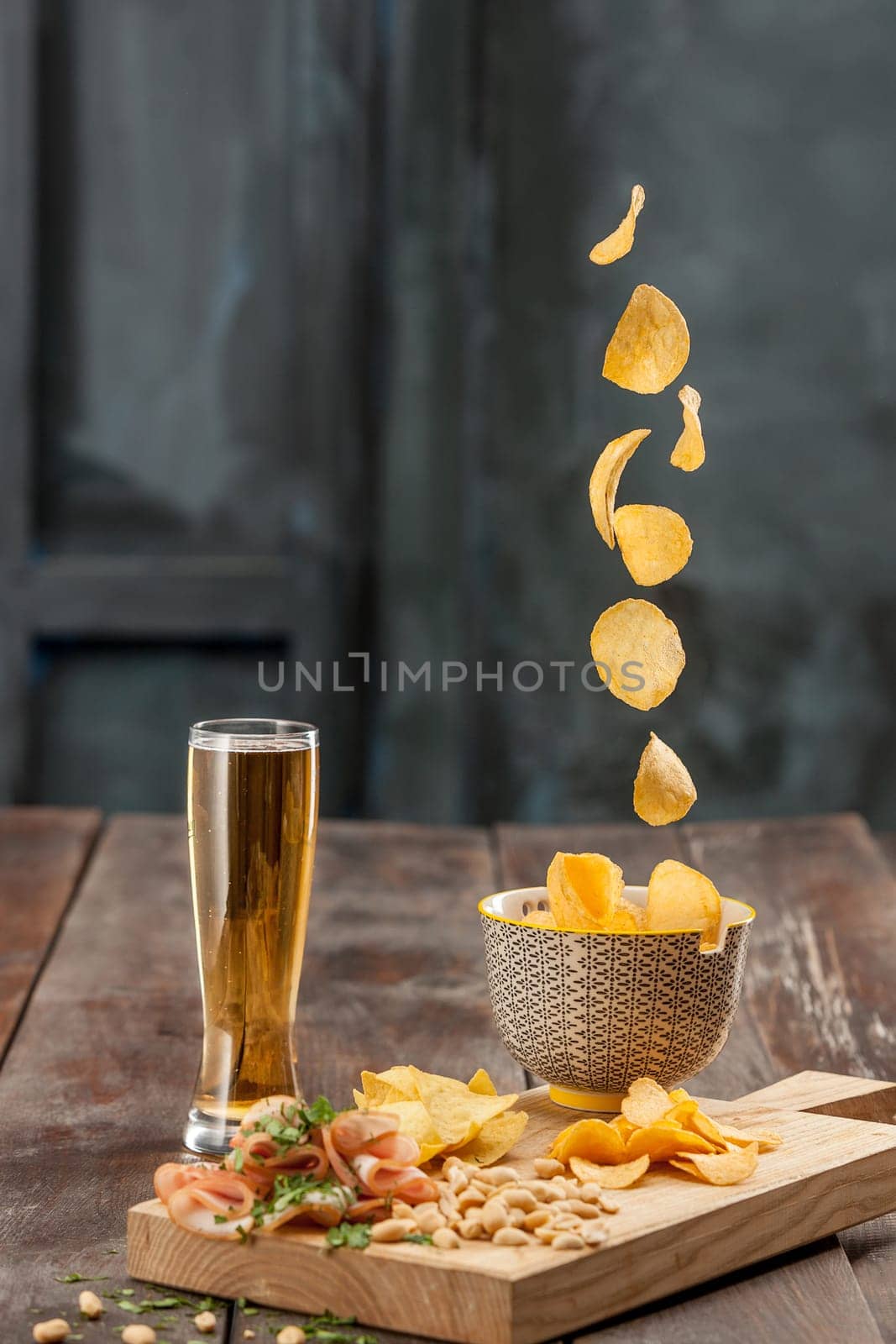 The glass of Beer and potato chips, pistachios isolated on a white