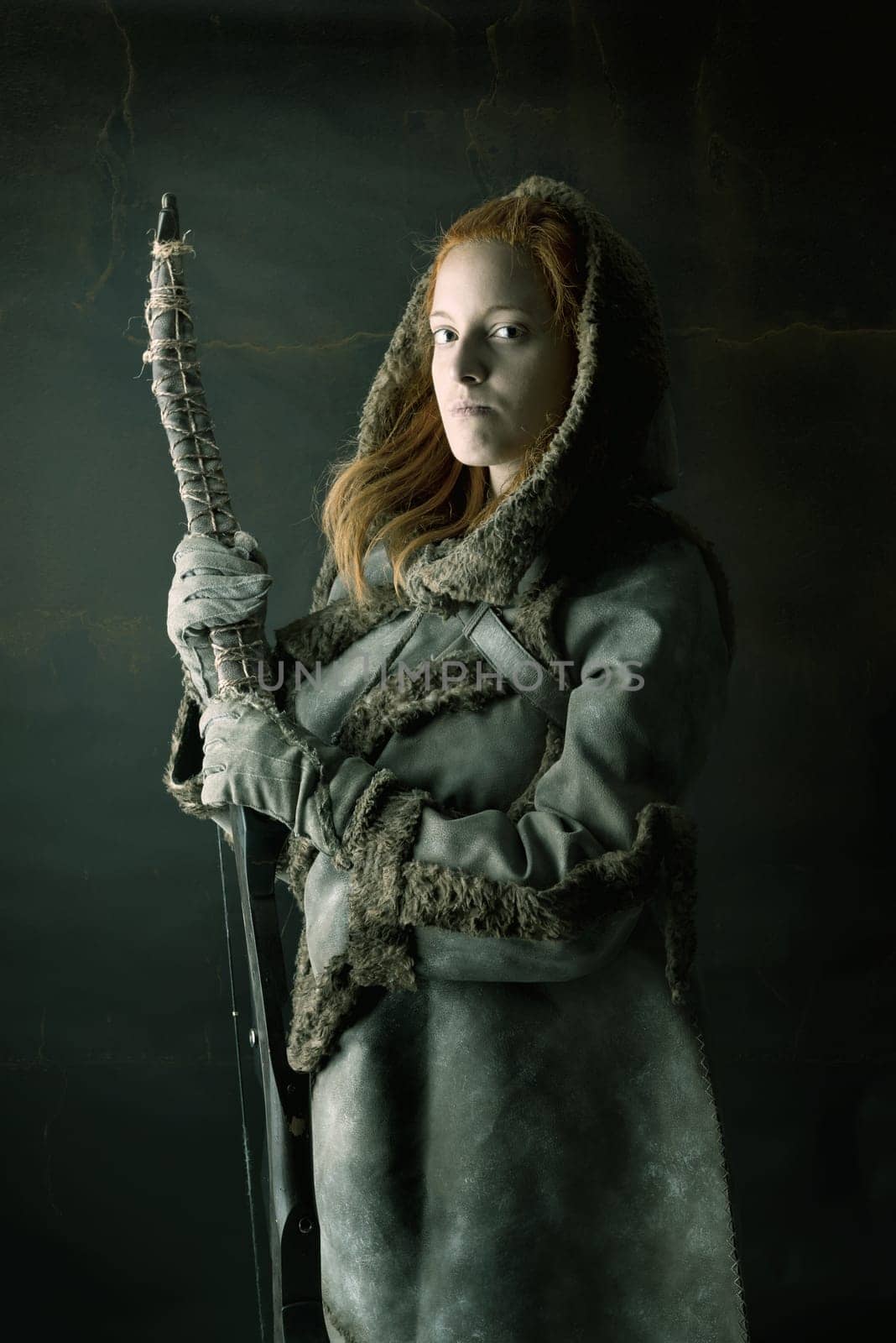 girl archer in a costume with bow isolated in a dark background