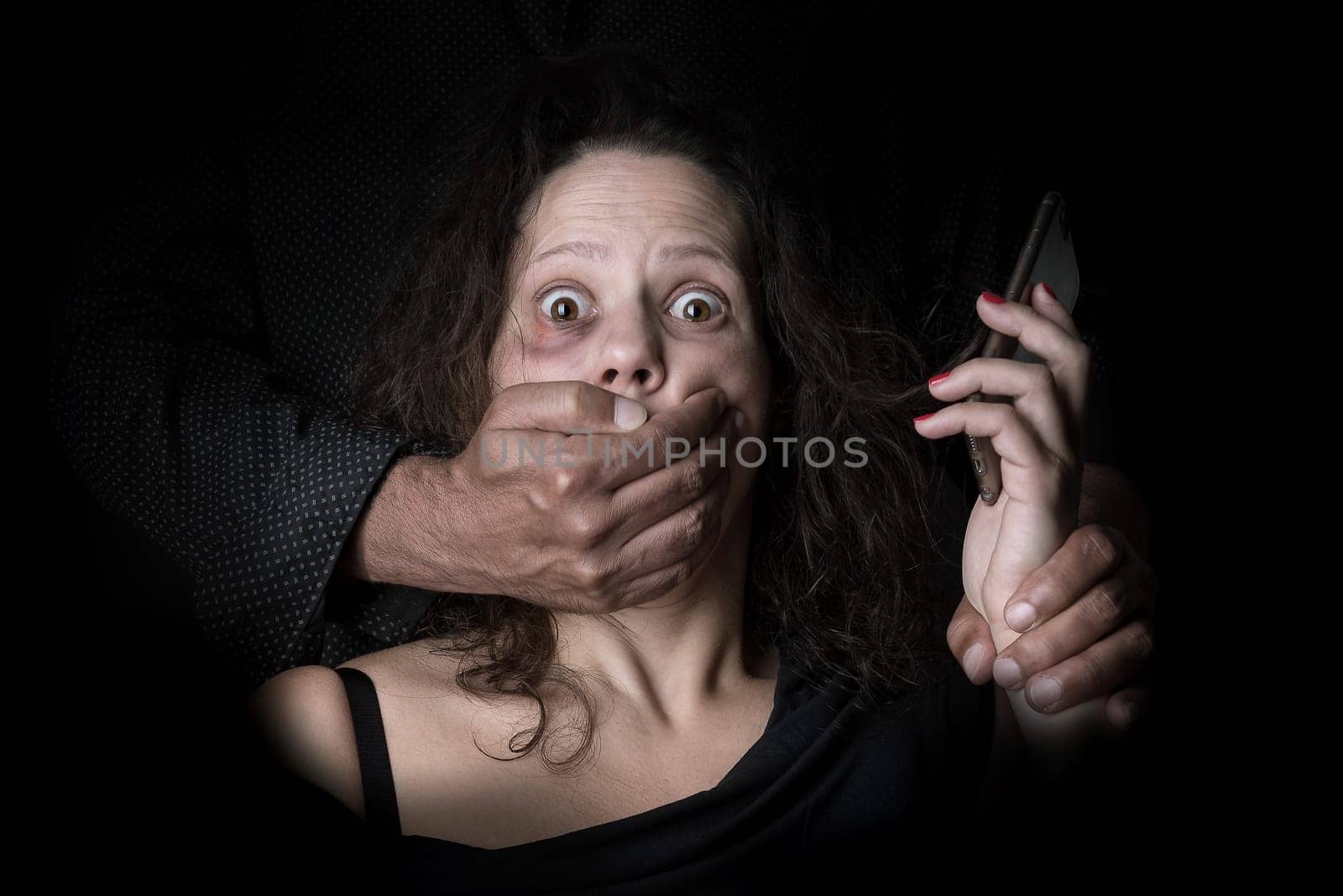 Abused woman trying to call for help with husband covering her mouth, victim of domestic violence