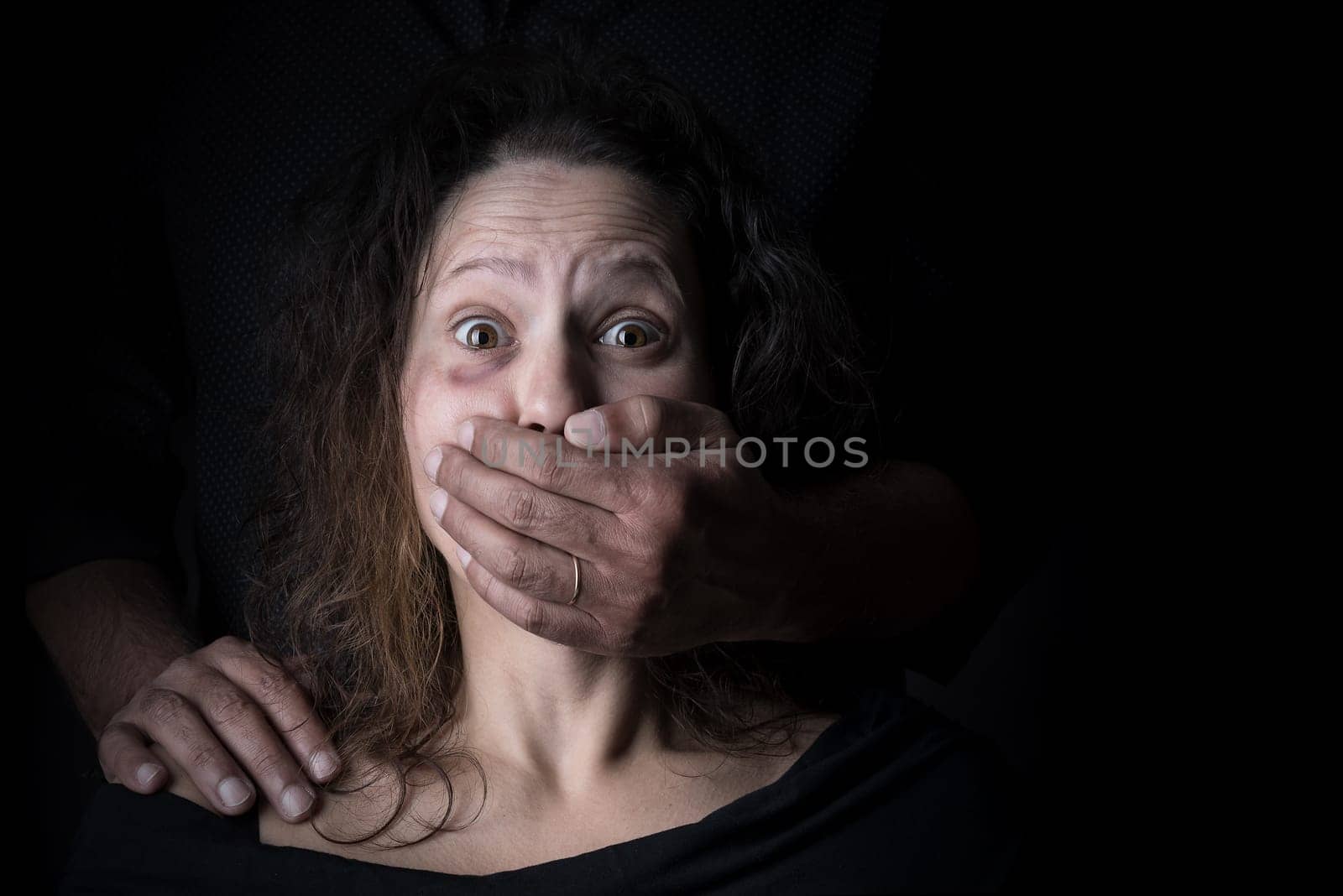 Scared woman with man's hand covering her mouth, victim of domestic violence
