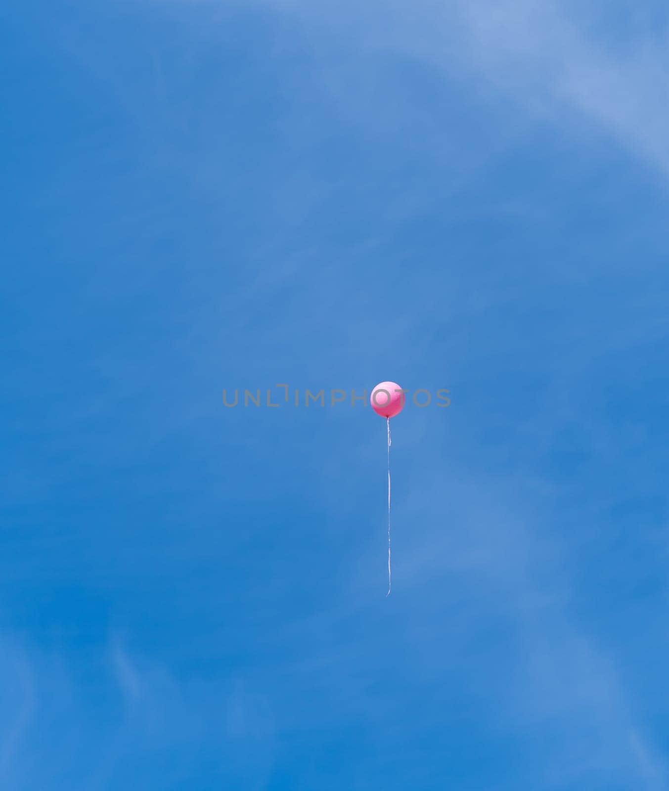 single pink balloon high in the sky