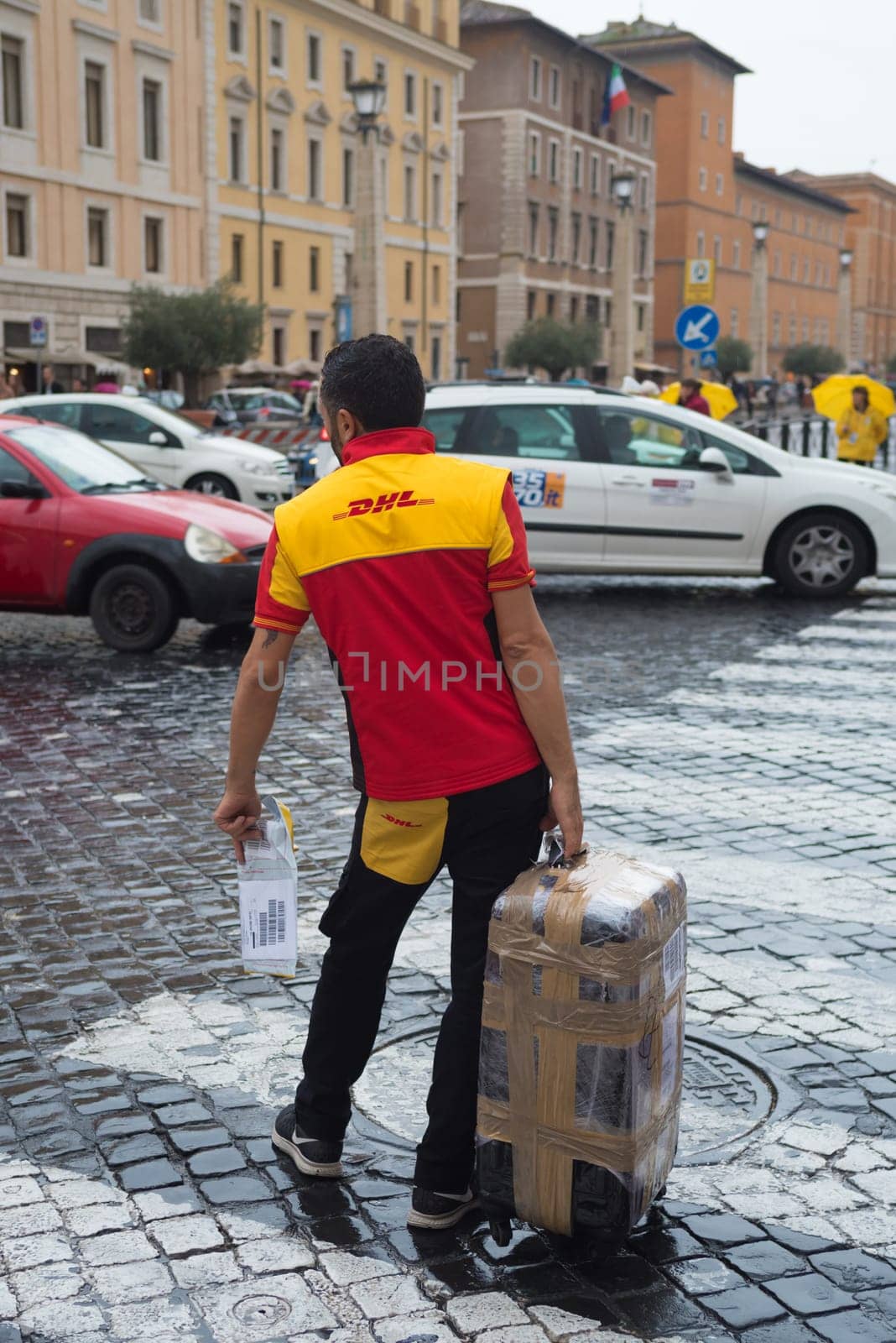 VATICAN CITY, VATICAN - OCTOBER 18, 2016: Unknown DHL courier with large package close to St peter's basilica