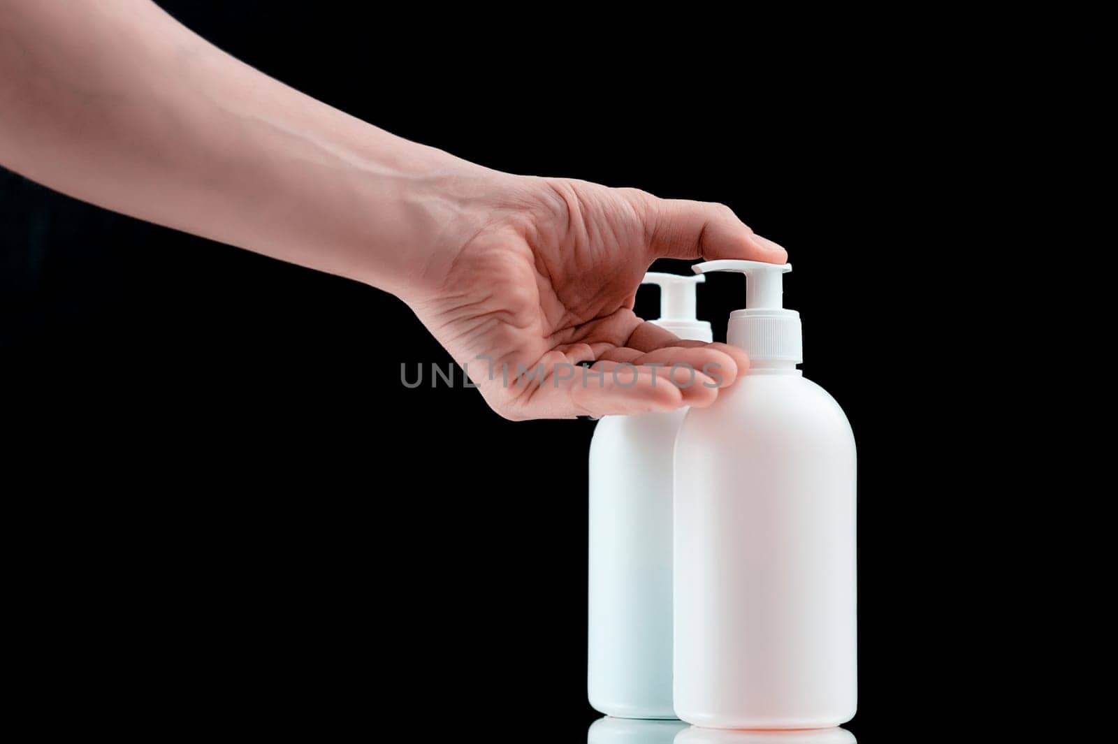 Plastic dispencer with liquid soap on a black background. Closeup