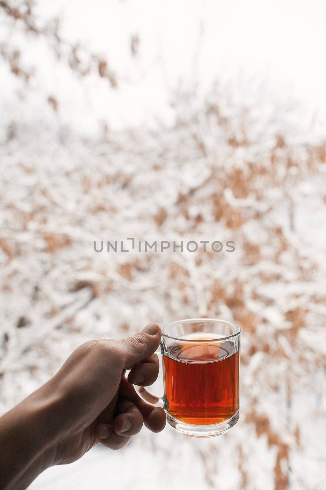 Transparent mug with tea. Hand holding a cup of tea. A mug of tea is hanging in the air. In the morning the composition creates a good mood.