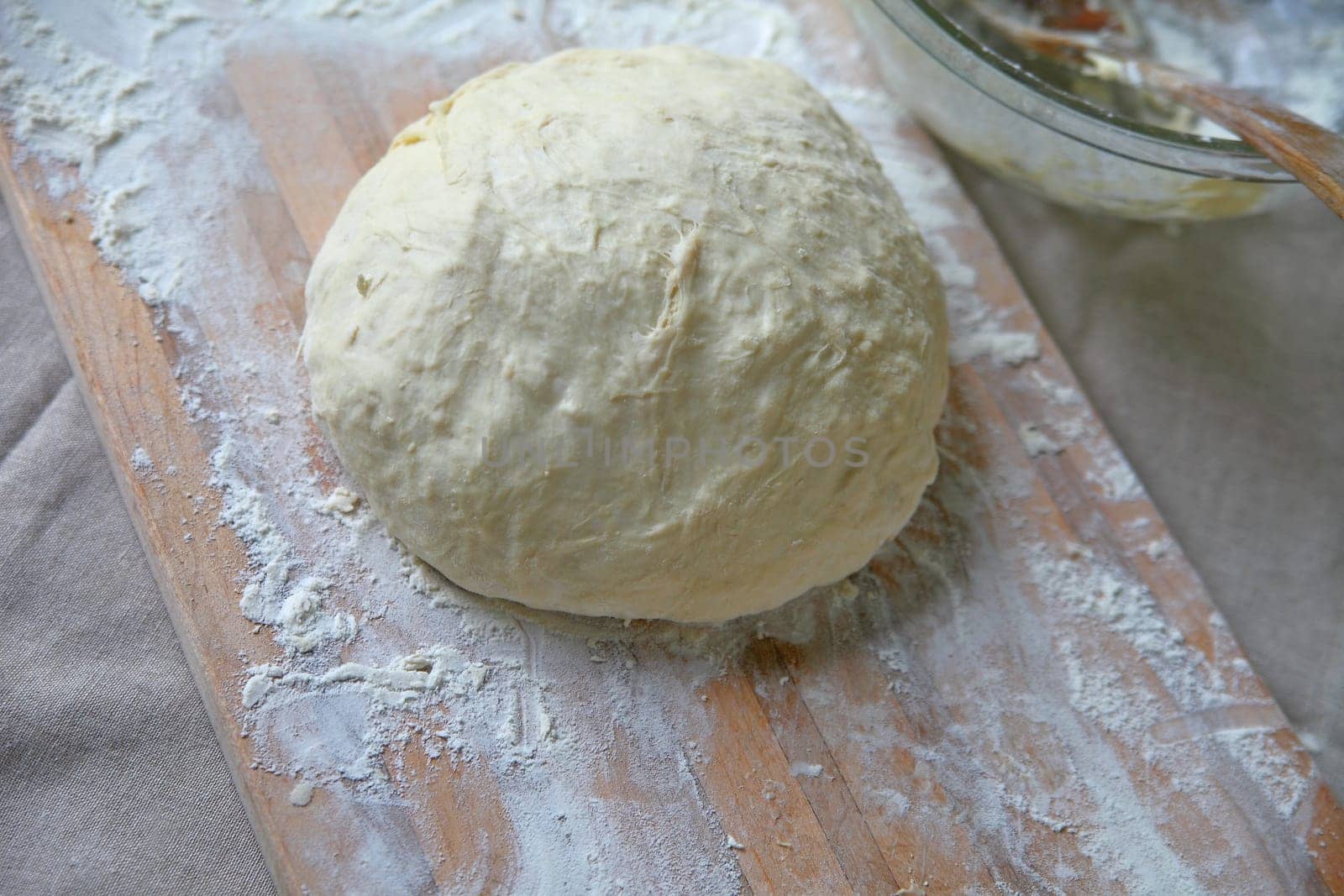 Ball of dough on a cutting board with napkin and mixing bowl