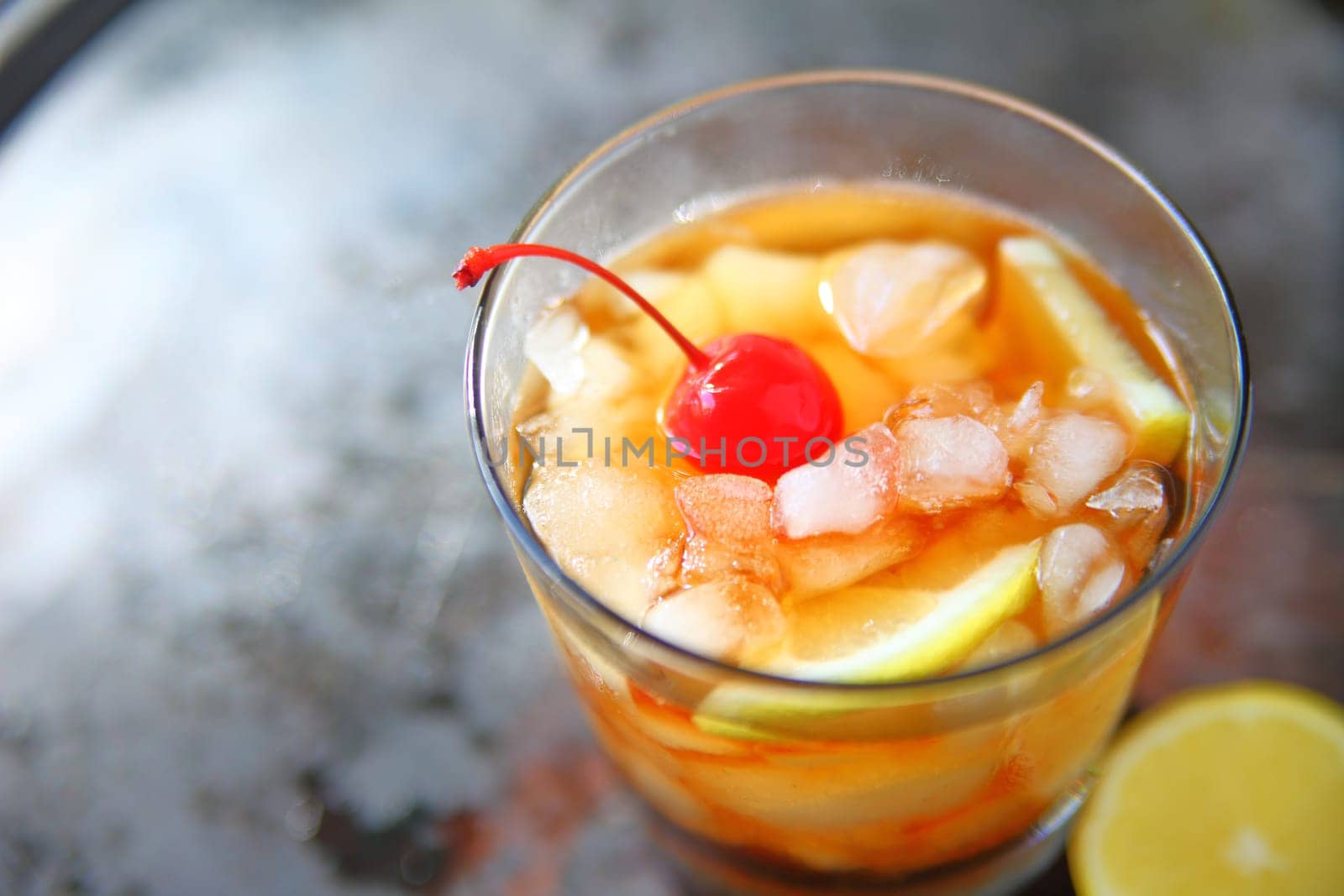 Overhead view of whiskey sour cocktail with lemon and cherry on crushed ice with room for text