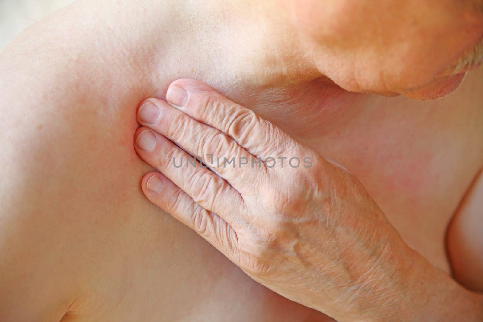 An older man with his hand on an area near his shoulder