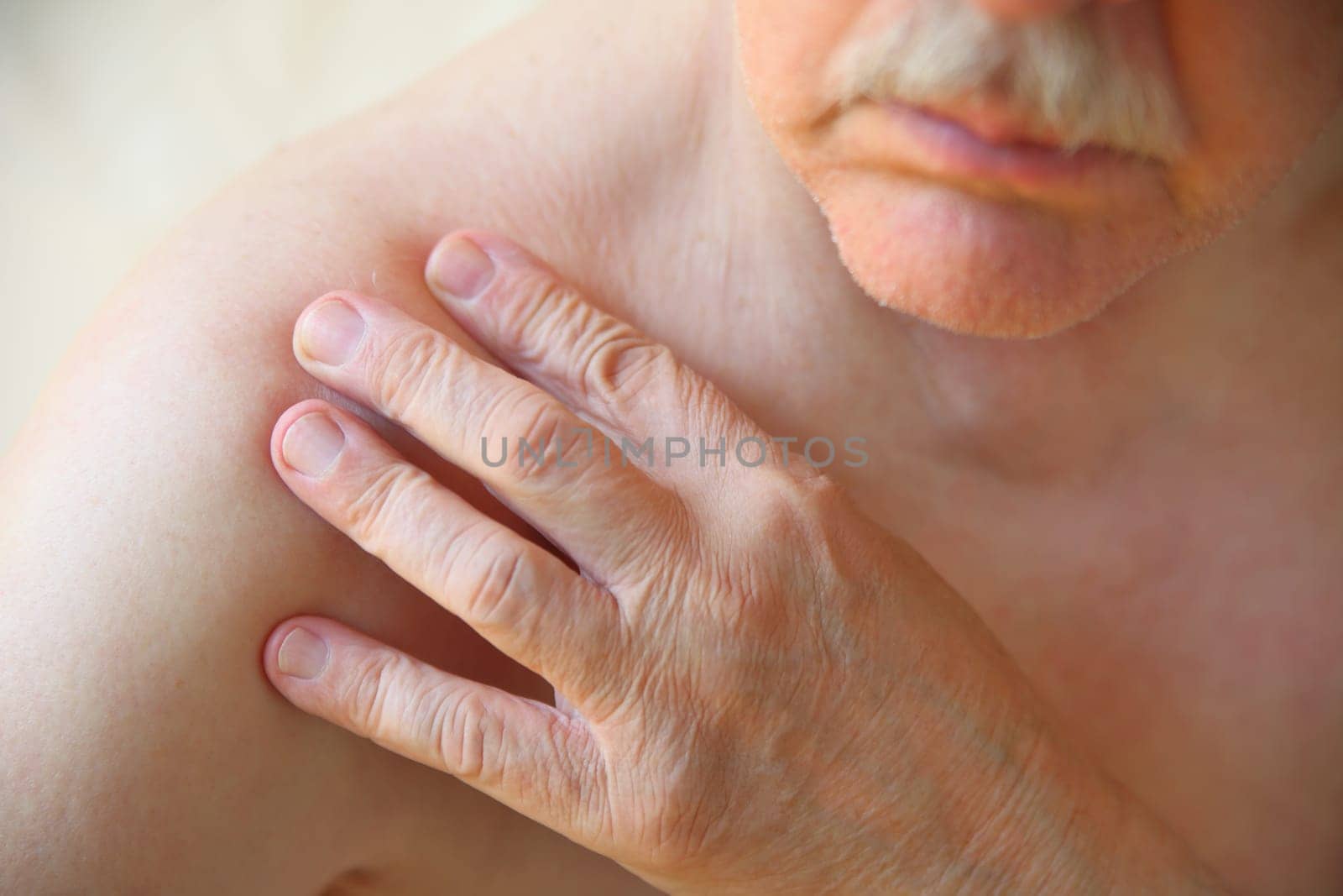 A senior man with his hand on a sore shoulder