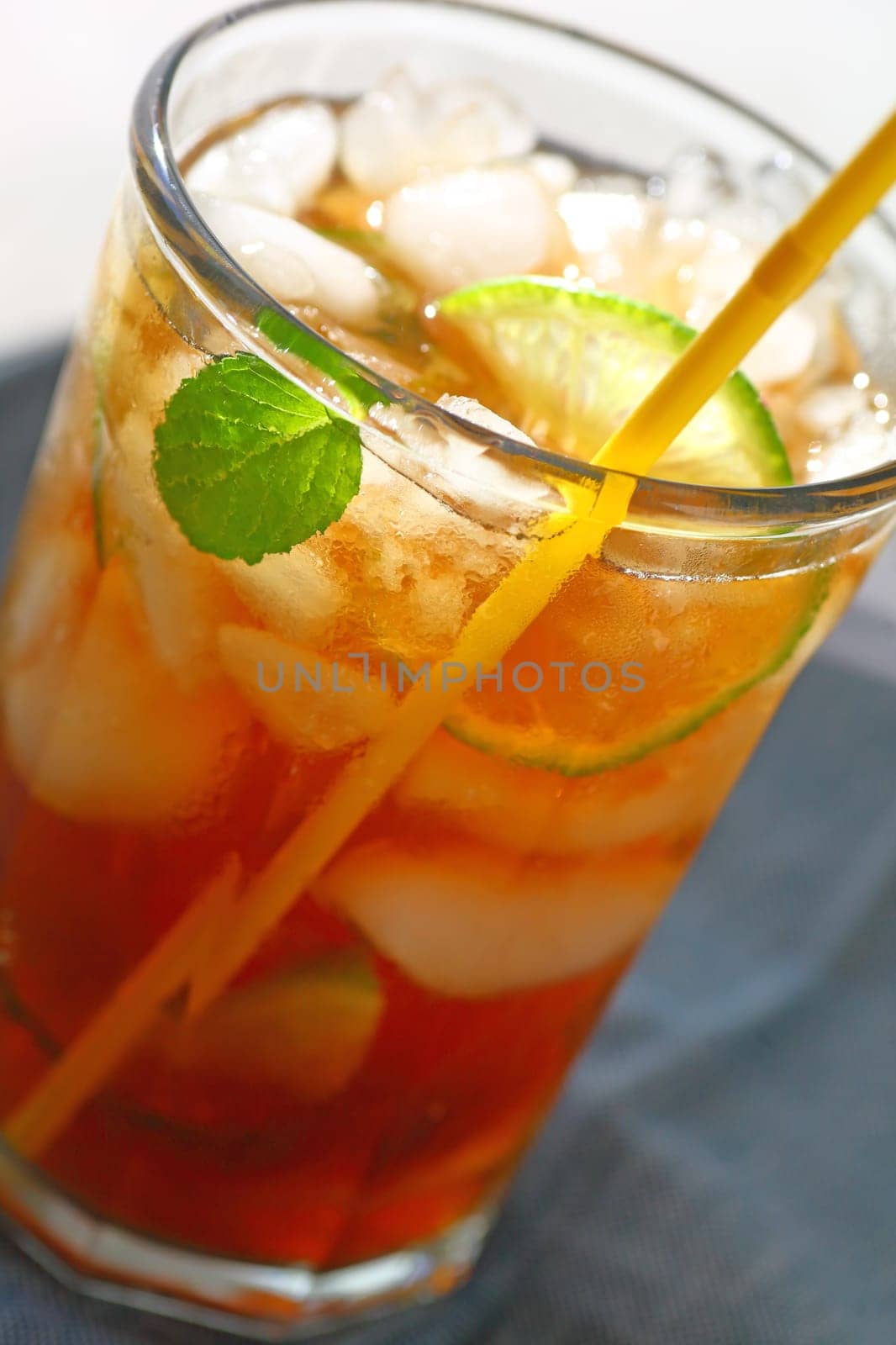Closeup view of iced tea with lime and mint, focus on condensation